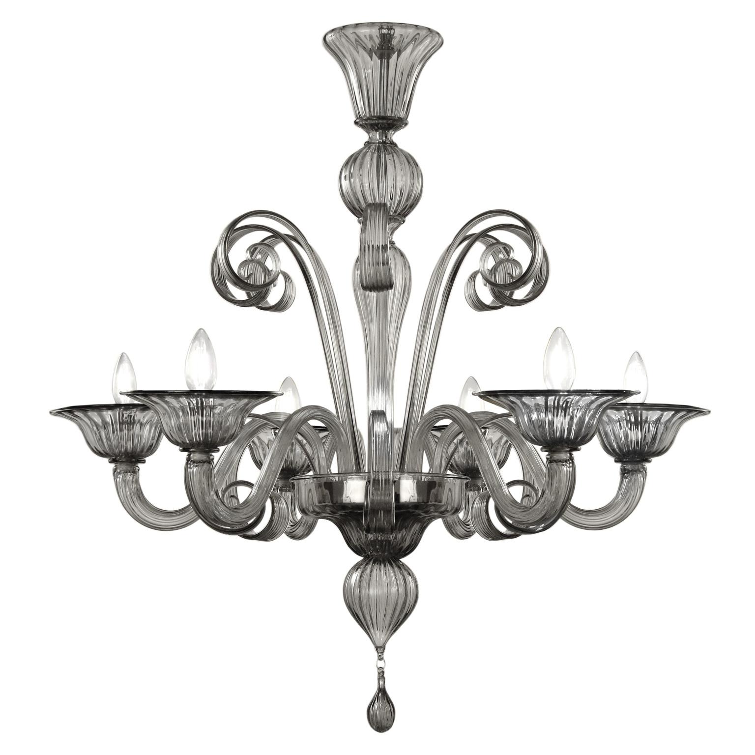 Capriccio by Multiforme is a 6 lights chandelier, in grey artistic glass, with curly ornamental elements.
Inspired by the Classic Venetian tradition it is characterized by a central column where many blown glass “pastoral” elements are installed.