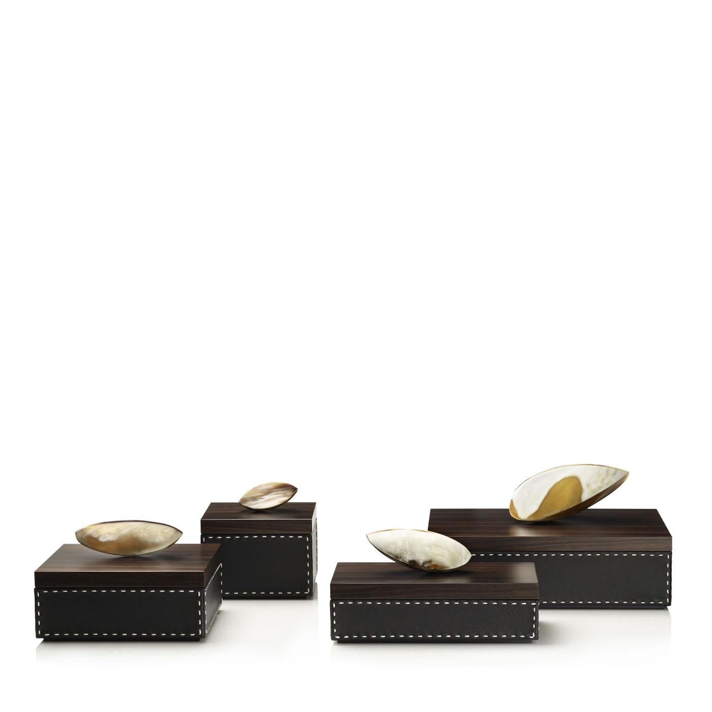 Capricia Box I by Arcahorn
Dimensions: D 13 x W 13 x H 15 cm
Materials: Leather, wood, horn.

Box in Aida pebbled leather, Onyx color with handmade ivory stitching. Lid in matte Amara ebony veneer with a sculptural horn handle.

Colors and shades of