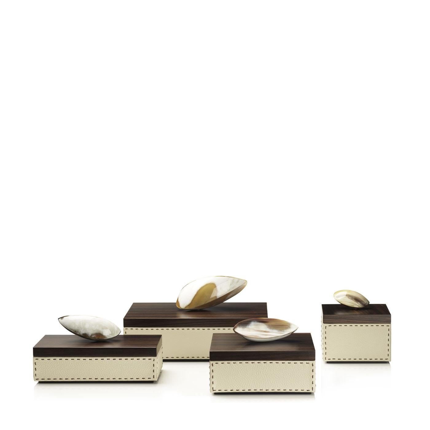 Capricia Box IV by Arcahorn
Dimensions: D 20 x W 28 x H 14 cm
Materials: Leather, wood, horn.

Box in Aida pebbled leather, Ice-cream color with handmade dark brown stitching. Lid in matte Amara ebony veneer with a sculptural horn handle. 	

Colors