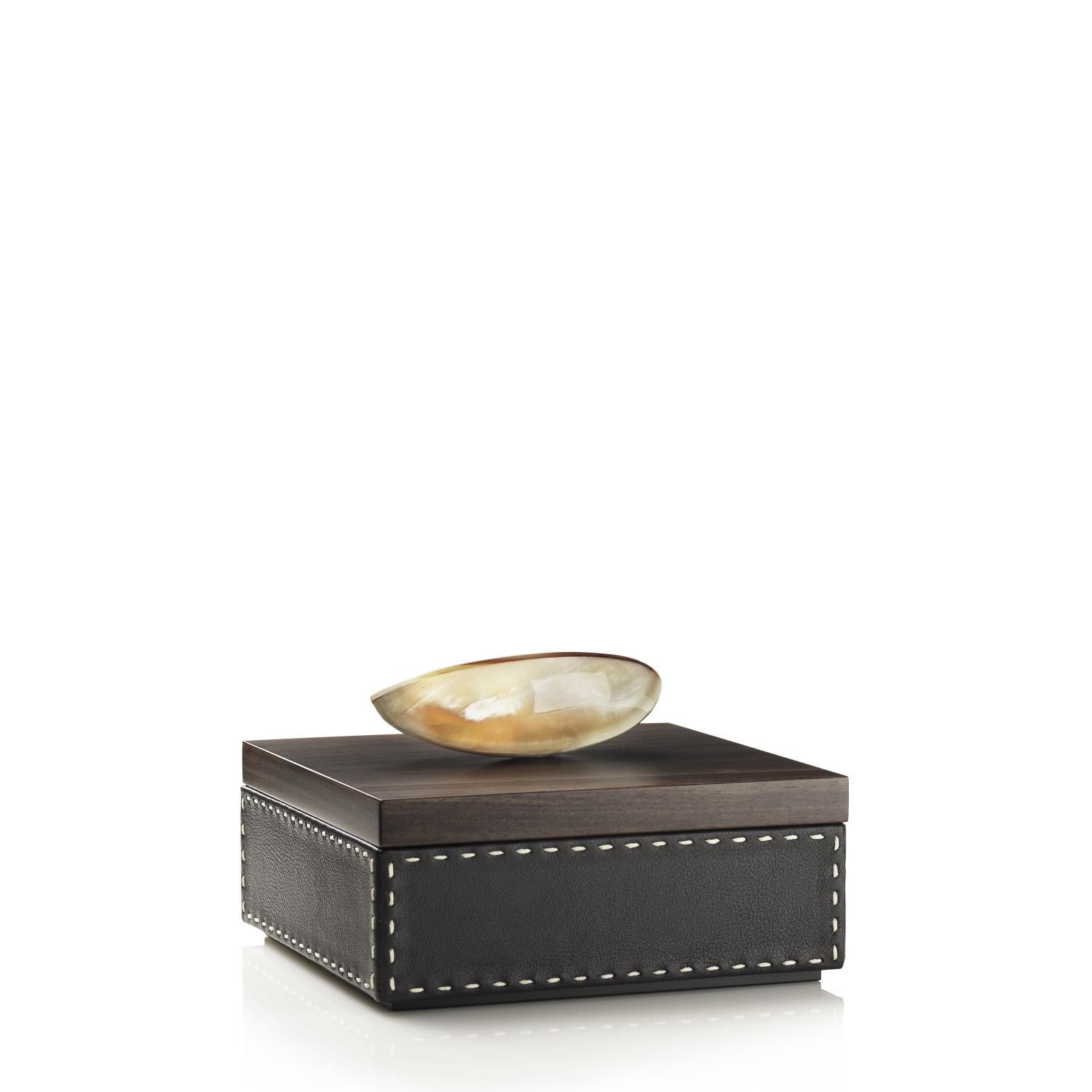 With its refined appearance, our Capricia square box can easily fit both traditional and contemporary décor. Its clean traditional shape is enriched by a lining in Onyx color pebbled leather with handmade cream-colored stitching. The interior is