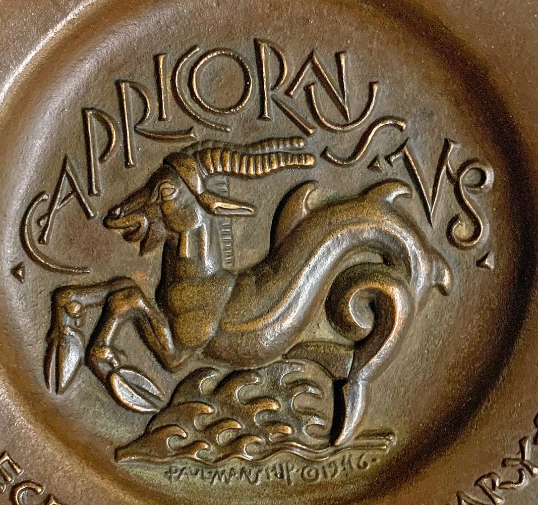 Audaz y brillantemente esculpida en altorrelieve, esta representación de una cabra marina (mitad cabra, mitad pez) -el símbolo clásico de Capricornio- fue esculpida por Paul Manship, el más importante escultor estadounidense creador de obras Art