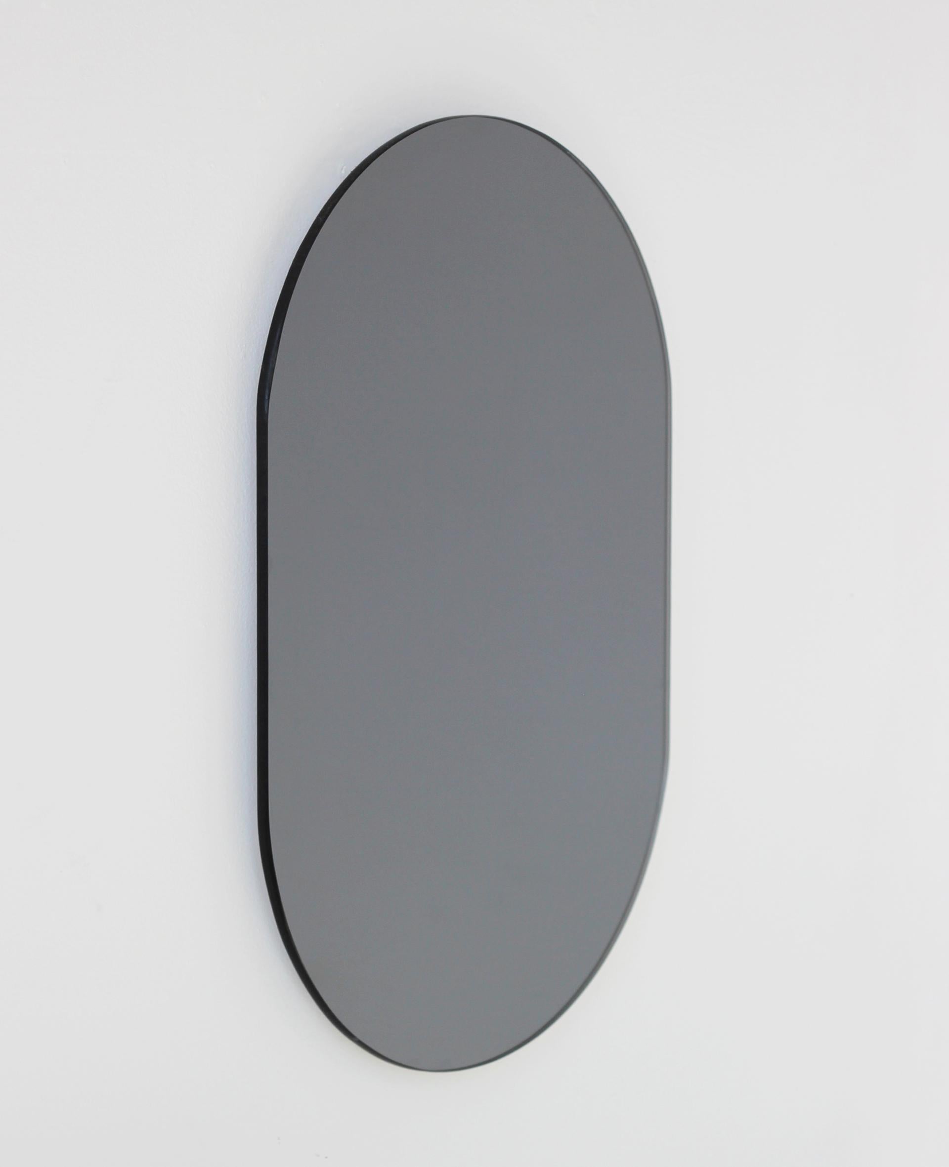 Minimalist capsule shaped black tinted frameless mirror. Quality design that ensures the mirror sits perfectly parallel to the wall. Designed and made in London, UK.

Fitted with professional plates not visible once installed for an easy and safe