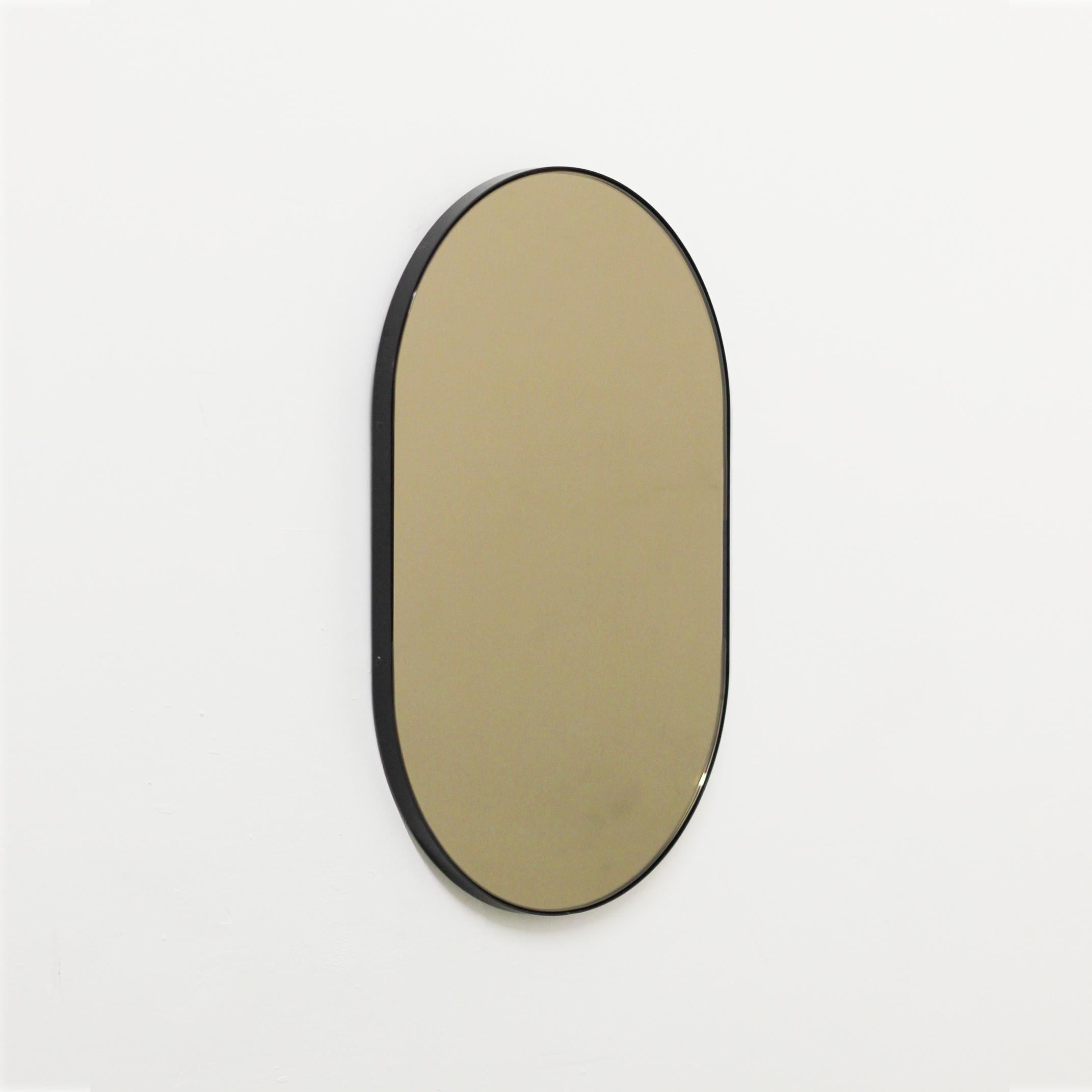 Modern handcrafted capsule shaped bronze tinted mirror with an elegant black powder coated aluminium frame. Designed and handcrafted in London, UK.

Fitted with a brass hook or an aluminium z-bar depending on the size of the mirror. Also available