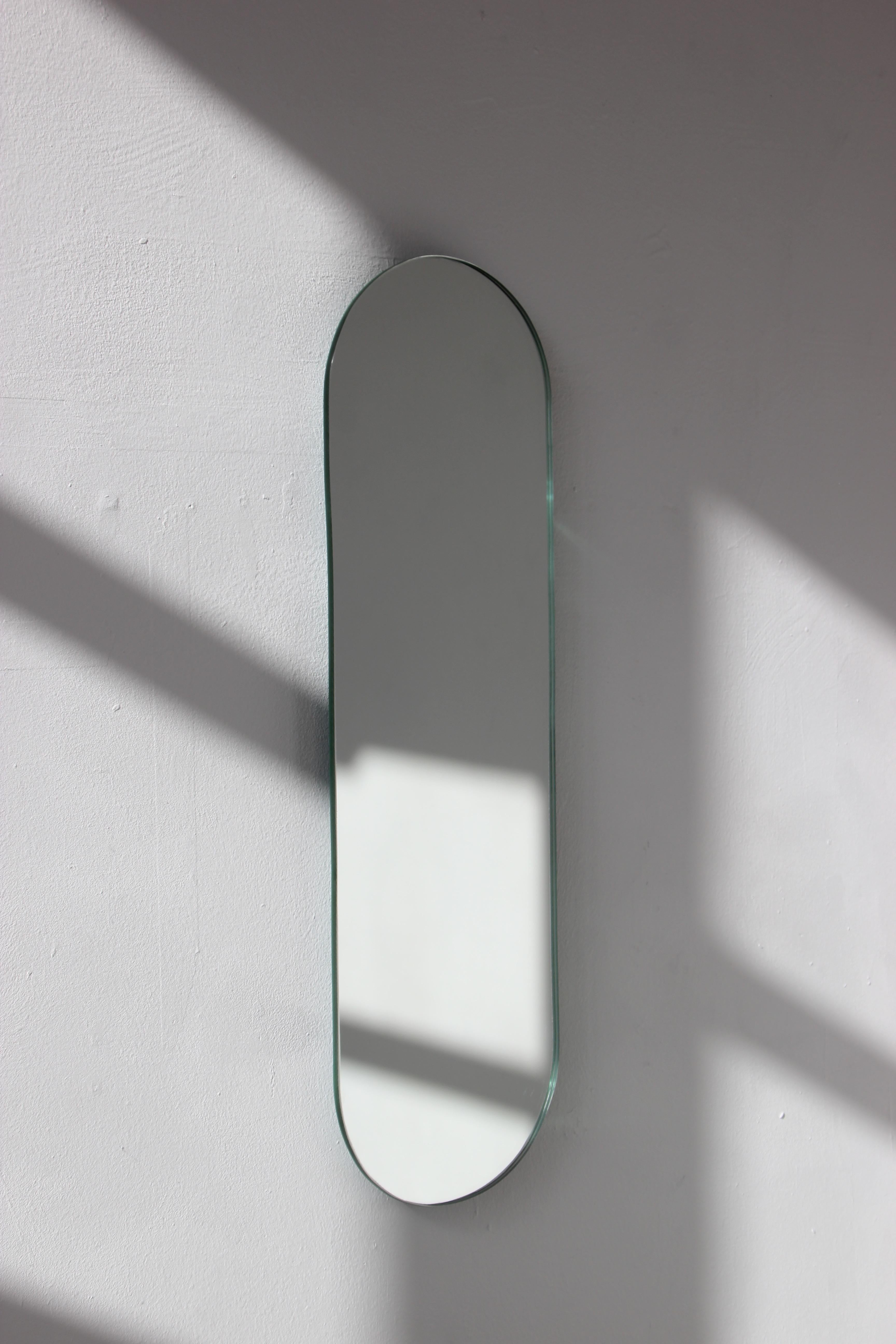 Minimalist capsule shaped frameless mirror. Fitted with a specialist hanging system that allows for the mirror to be hung in two different positions. Designed and handcrafted in London, UK.

The images show a small size mirror, measuring 27cm x