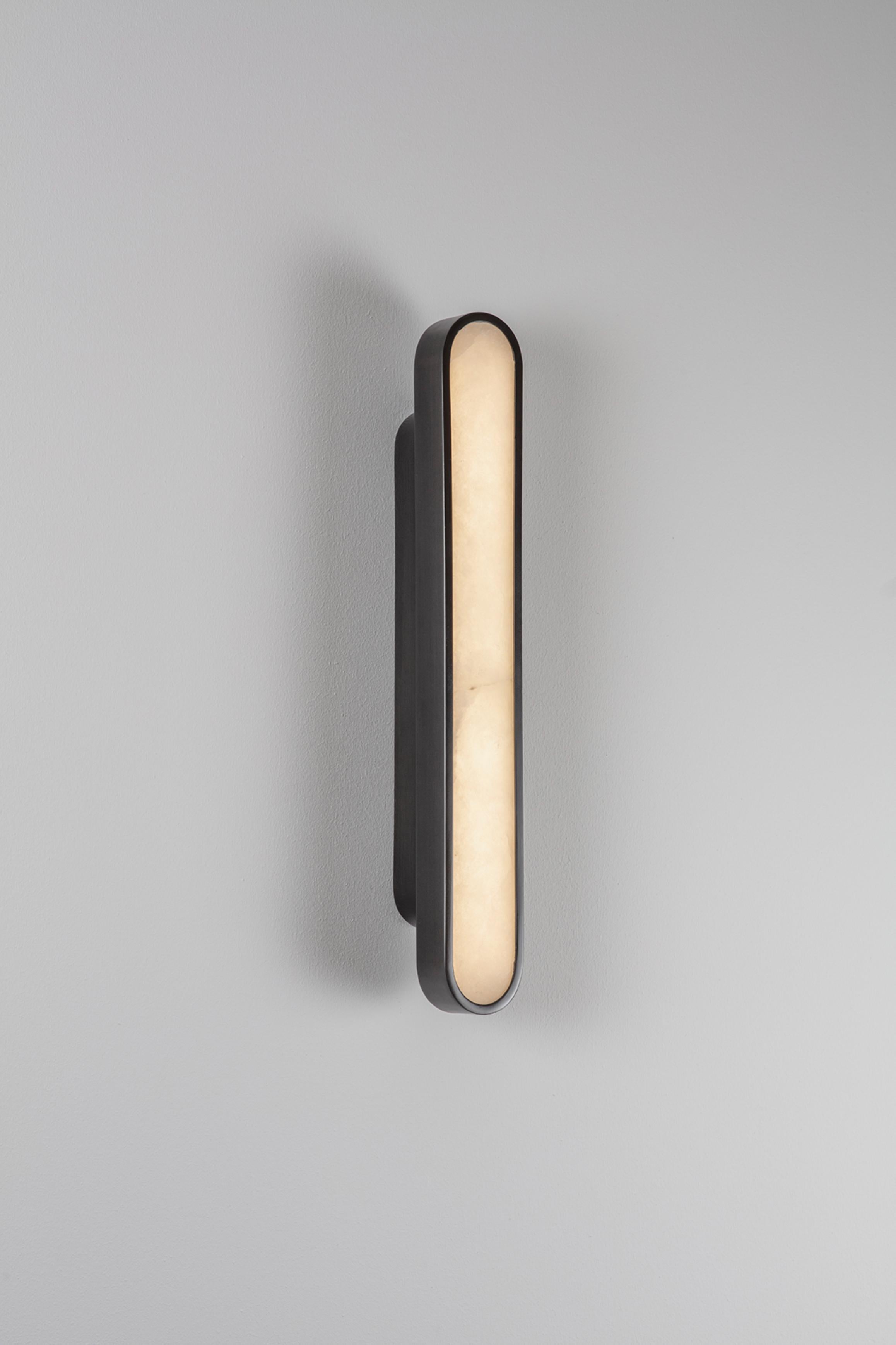 Capsule black wall light by Square in Circle
Dimensions: D 5 x W 5.5 x H 40 cm
Materials:Brushed brass/ opaque glass
Other finishes available.

Perfect rounded rectangular shape wall light. Metal wall light is neatly fixed with the same shape