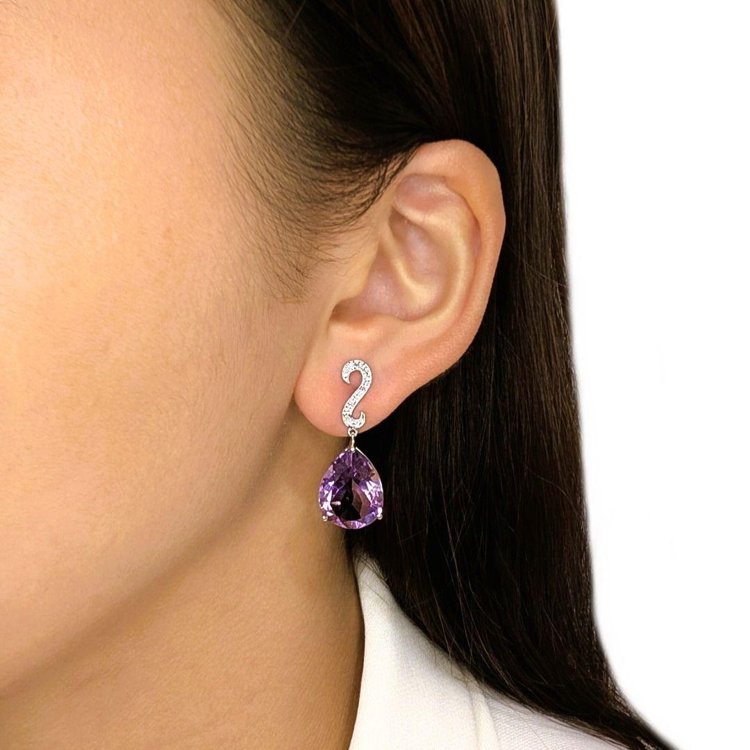 A statement of grandeur and elegance, these earrings feature two pear-shaped amethysts with a combined weight of 14.3ct, radiating a rich and captivating purple hue. Accenting the center stones are 14 round brilliant-cut natural diamonds totaling