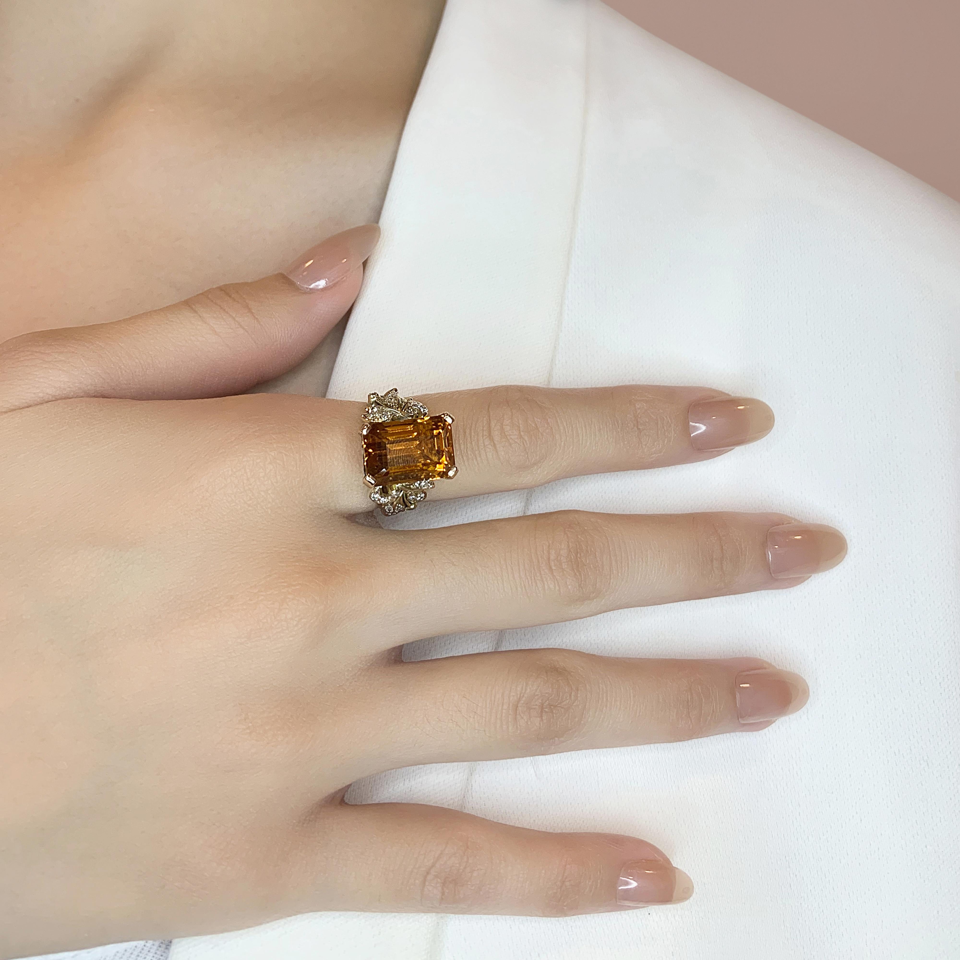 Ajoutez une touche d'opulence avec cette magnifique bague, magistralement réalisée en or jaune 14 carats. La pièce maîtresse est une époustouflante citrine de 14,3ct en forme d'émeraude, qui rayonne d'une teinte orange vibrante. La pierre principale
