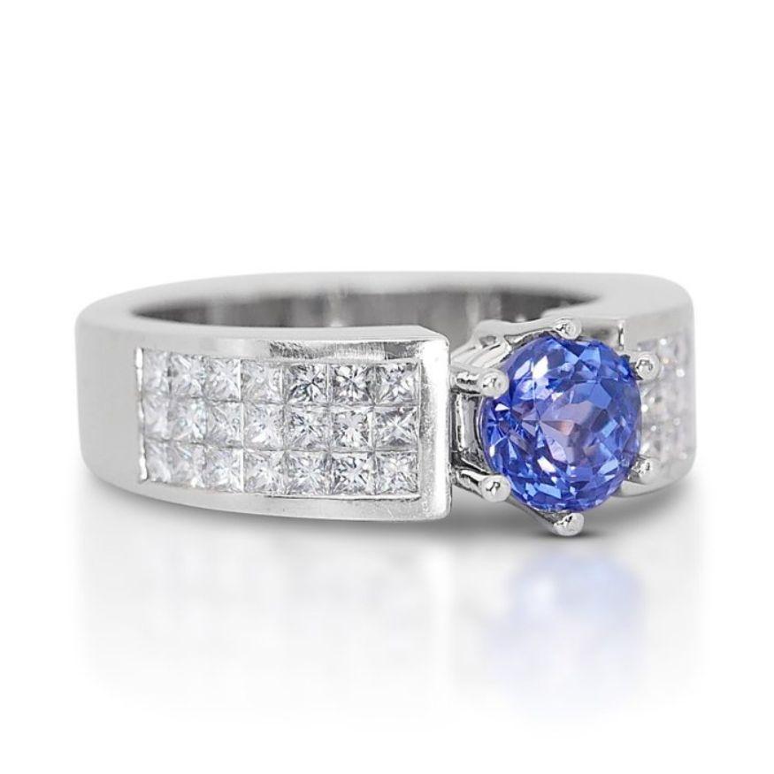 This captivating ring showcases a dazzling 1.50-carat round tanzanite as its centerpiece, radiating a deep violetish blue hue that exudes sophistication and allure. With its transparent clarity, the tanzanite displays its natural beauty, allowing