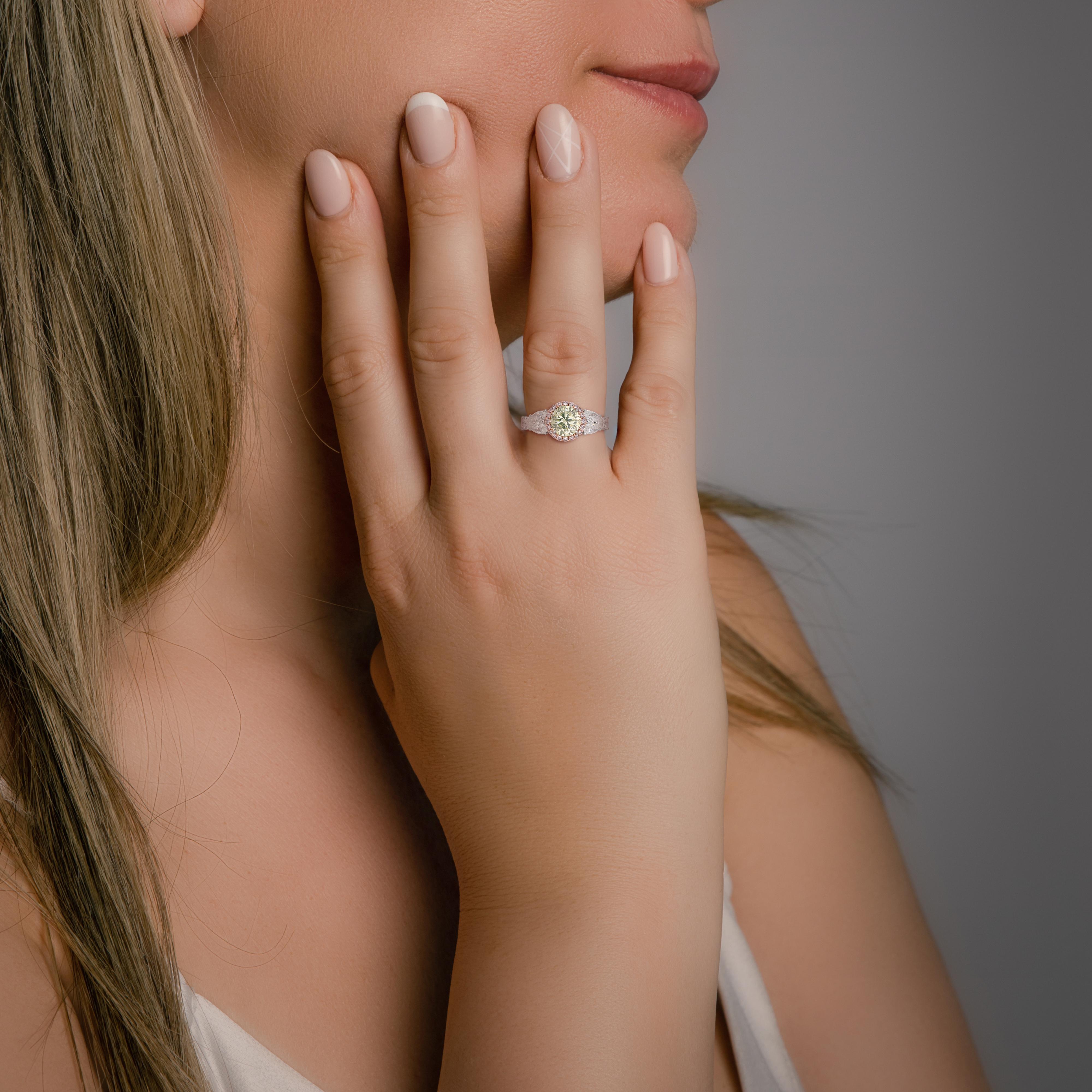 Cette bague spectaculaire est ornée d'un diamant vert clair fantaisie comme pierre principale, pesant 1,53 ct et d'une teinte envoûtante. La pierre centrale est accentuée par un halo de six diamants de taille princesse (0,98ct) de couleur E et de