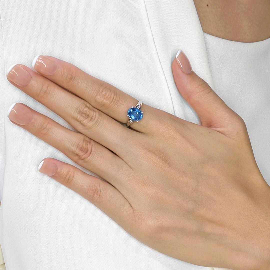 Embrace the serene beauty of the ocean with this captivating 18K white gold ring, a true testament to elegant design. At its core, a magnificent 2.68ct natural oval-cut blue topaz radiates a mesmerizing, deep blue hue, reminiscent of tranquil