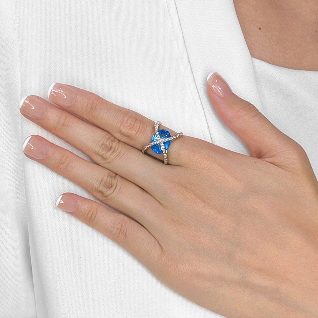 Make a stunning statement with this exceptionally stylish ring, showcasing a magnificent oval-cut blue topaz embraced by brilliant diamonds in sleek 18K white gold. The centerpiece is a breathtaking 5.69-carat natural blue topaz, displaying a vivid,