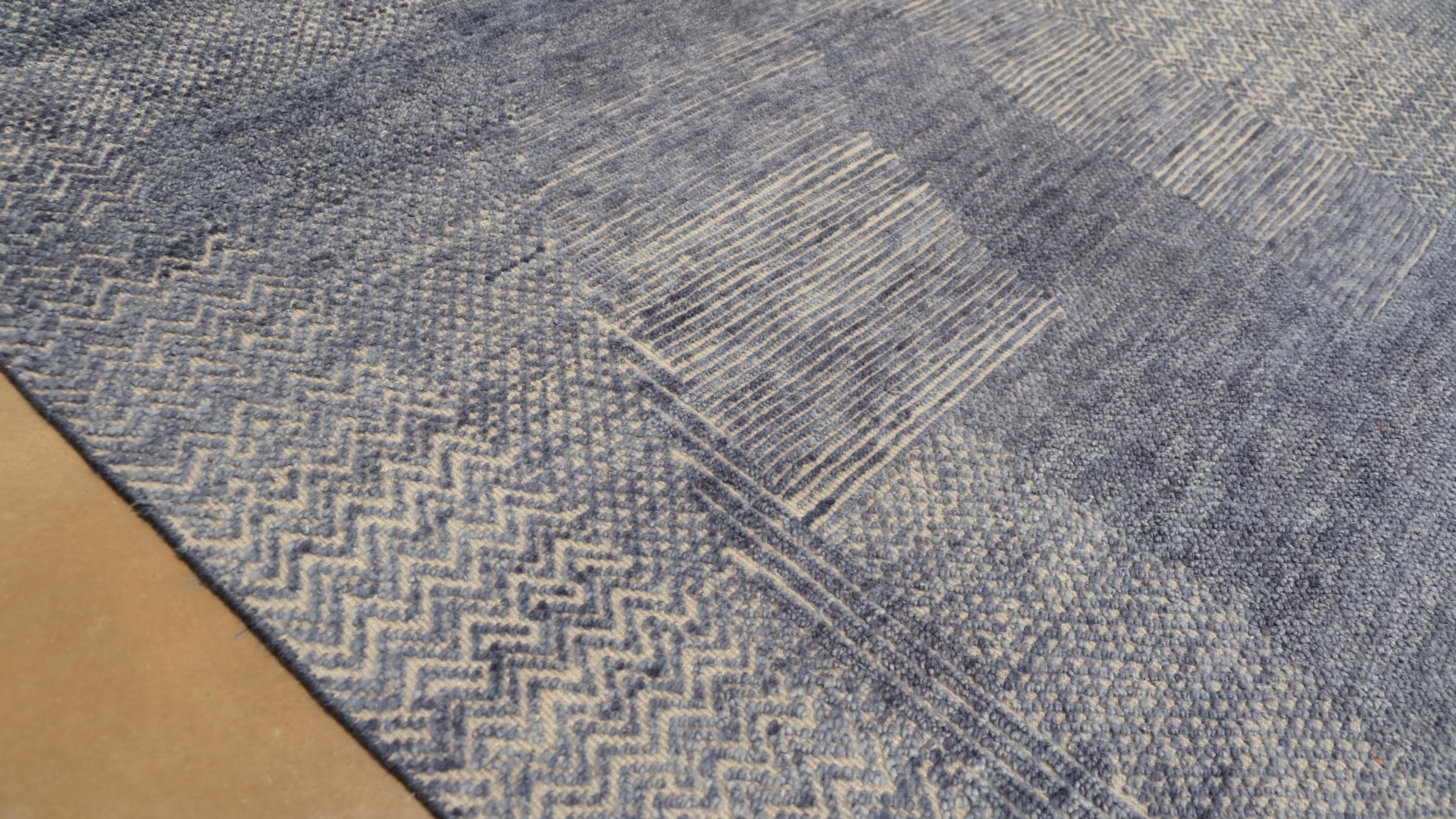 Verleihen Sie Ihrem Interieur mit diesem handgeknüpften Wollteppich einen raffinierten Hauch von Kunstfertigkeit. Dieser Teppich mit seinem modernen, abstrakten Design besticht durch ein fesselndes Zusammenspiel von Blau- und Grautönen mit einer