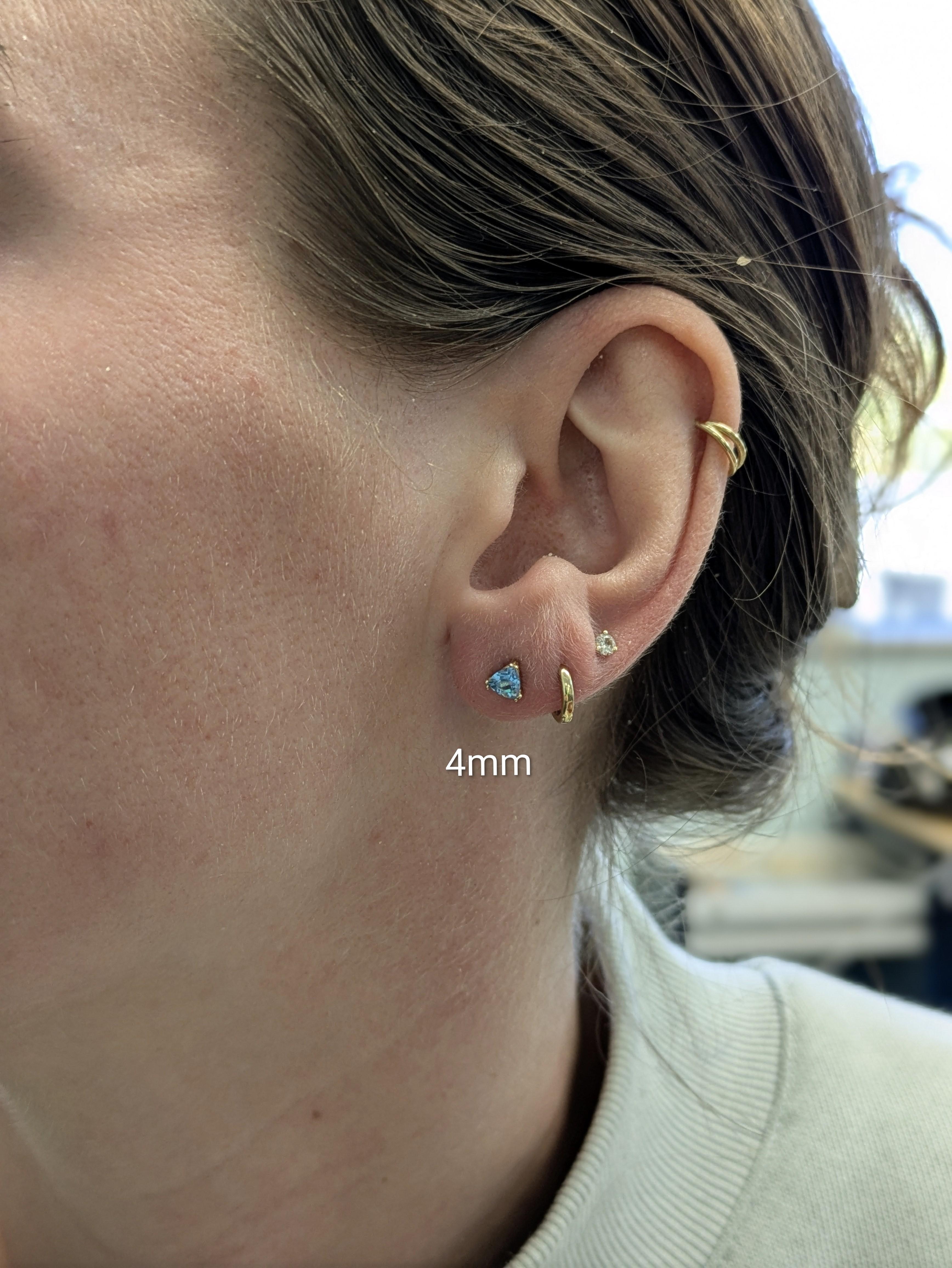 Irradia brillantezza con queste scintillanti borchie solitarie in topazio blu svizzero, incastonate in oro massiccio 14k. Le gemme con taglio trilione da 4 mm scintillano con un vibrante fuoco blu per un look elegante e senza sforzo.

