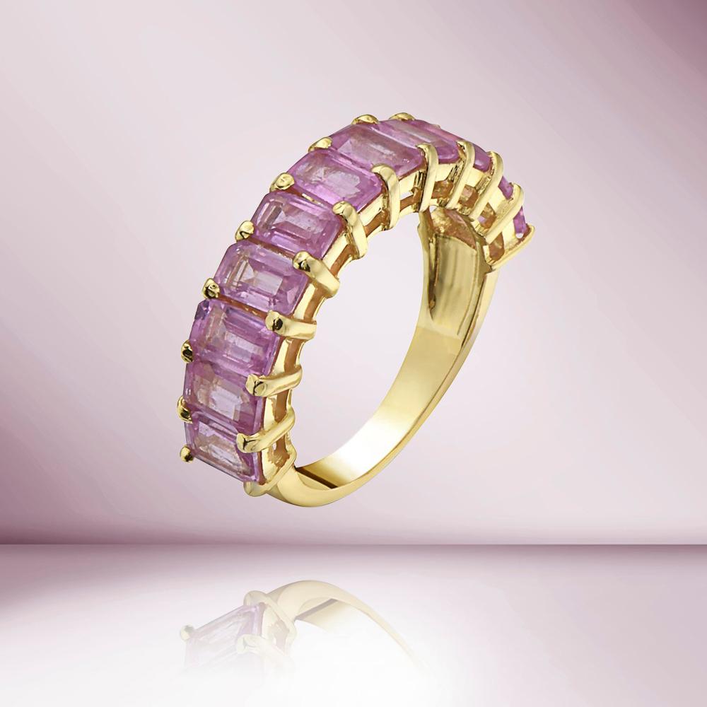 The Emerald Cut Pink Sapphire HalfWay Eternity Band Ring (4.50 ct.) in 14K Gold is a beautiful and feminine piece of jewelry that features a continuous row of emerald cut pink sapphires in a half-way eternity band design. The sapphires are set in a