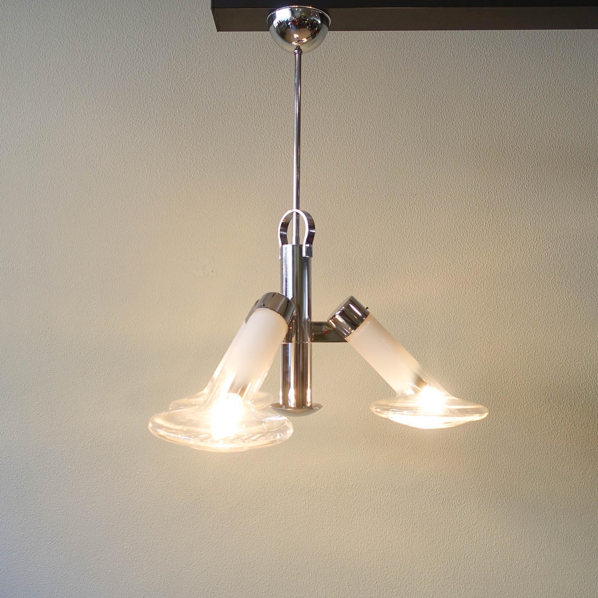 Questa lampada da soffitto è stata disegnata da Carlo Nason per Mazzega, in Italia, durante gli anni '70. Presenta tre bicchieri ispirati ai fanali delle auto e colorati di bianco latte che sfumano verso il traslucido creando una luce diffusa. Il