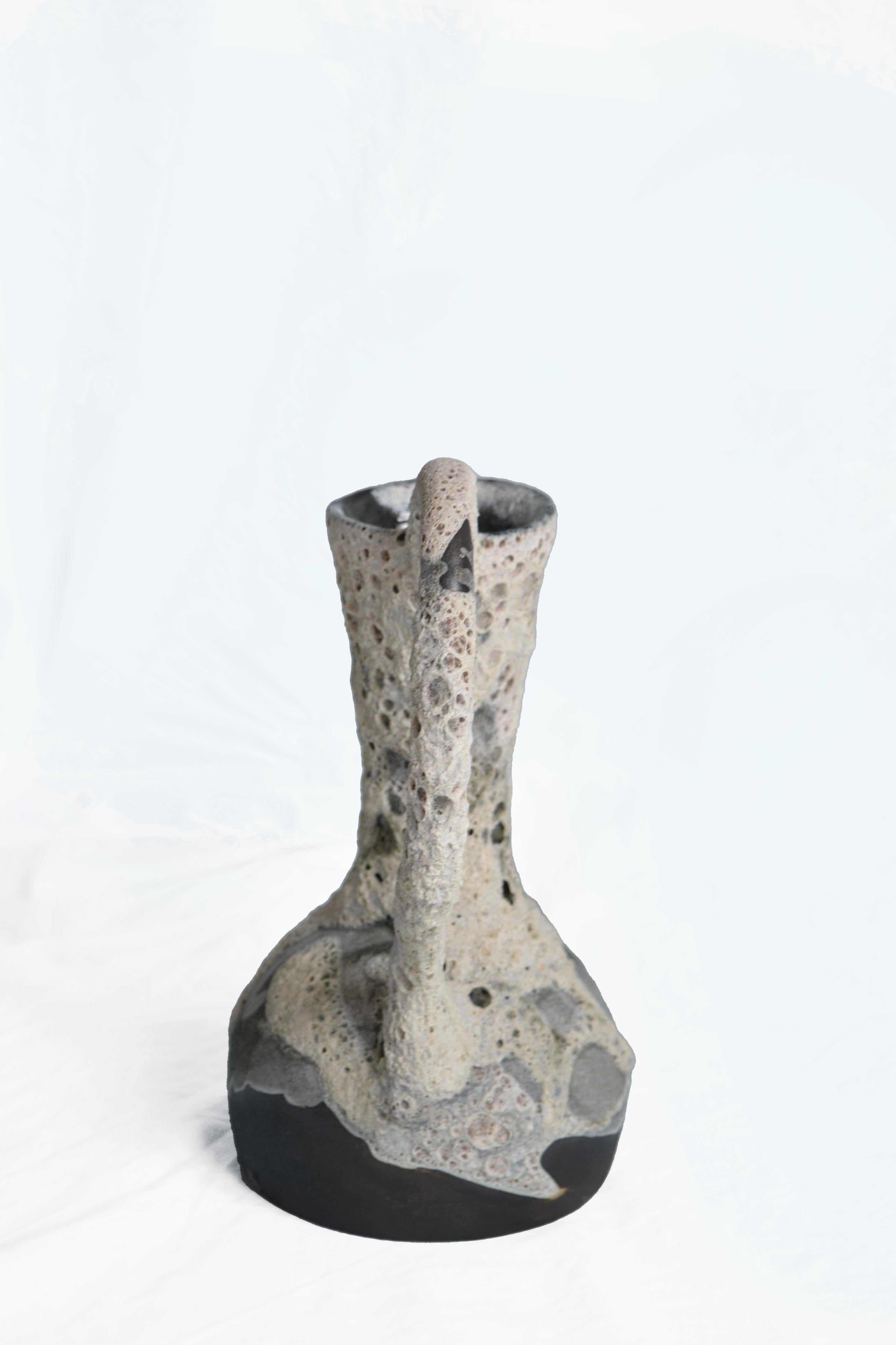Vaso Carafe 6 di Anna Karountzou
Dimensioni: L. 21,5 x P. 15 x H. 30 cm
Materiali: argilla in gres nero, smalto trasparente all'interno, smalto a cratere fatto a mano all'esterno, cottura a 1220

Nata e residente ad Atene, in Grecia, con un