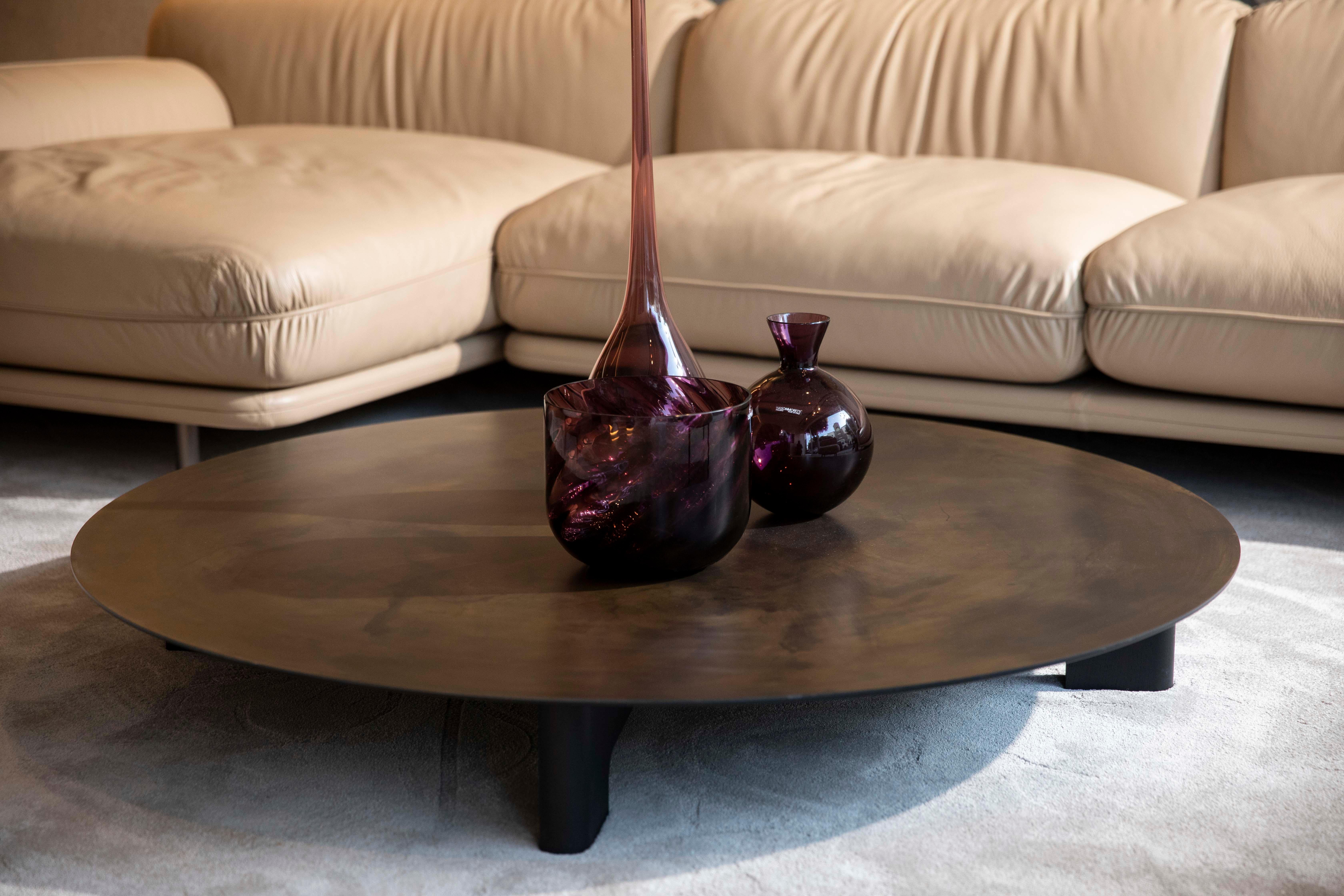Carato is a unique coffee table with a large and thin metal disc serving as a support surface. It comes in three different sizes and can be used as a center table or a side table for a sofa, depending on the disc's height and size. The table