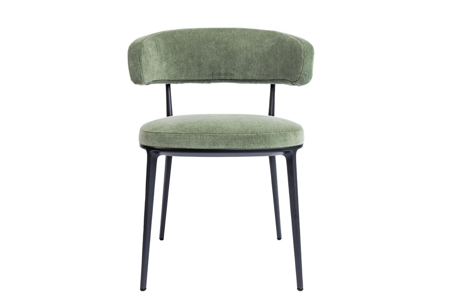 Caratos is a series of upholstered dining chairs by Maxalto, with a die-cast aluminum frame that have contemporary lines. These chairs are upholstered in a sage-colored velvet and the frame is finished in painted graphite. The Caratos chairs are