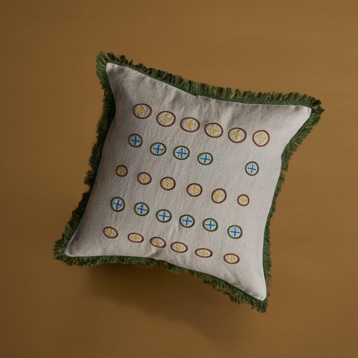 Le coussin design Cardamome est fabriqué à partir d'un lin beige naturel avec des cercles brodés contrastés. La finition de la frange est entièrement réalisée à la main. Livré sans garniture, les garnitures en plumes de canard peuvent être