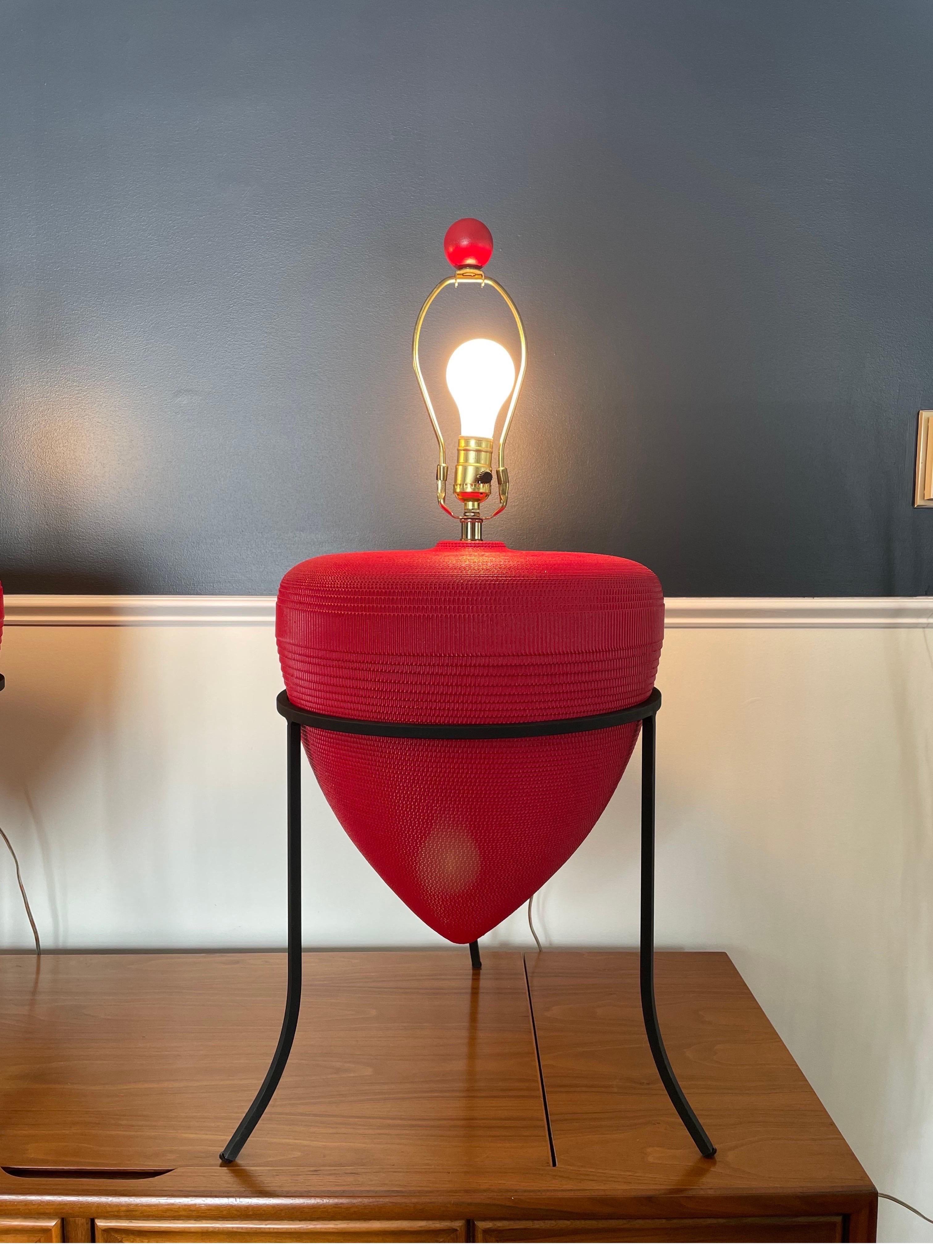 Jaw Dropping pair of urn lamps complete with original shades is from the 80’s or 90’s. Produced from wrapped corrugated cardboard, these unique urn lamps sit in a wrought iron tripod stand. POP of color in amazing red! In the style of Frank Gehry