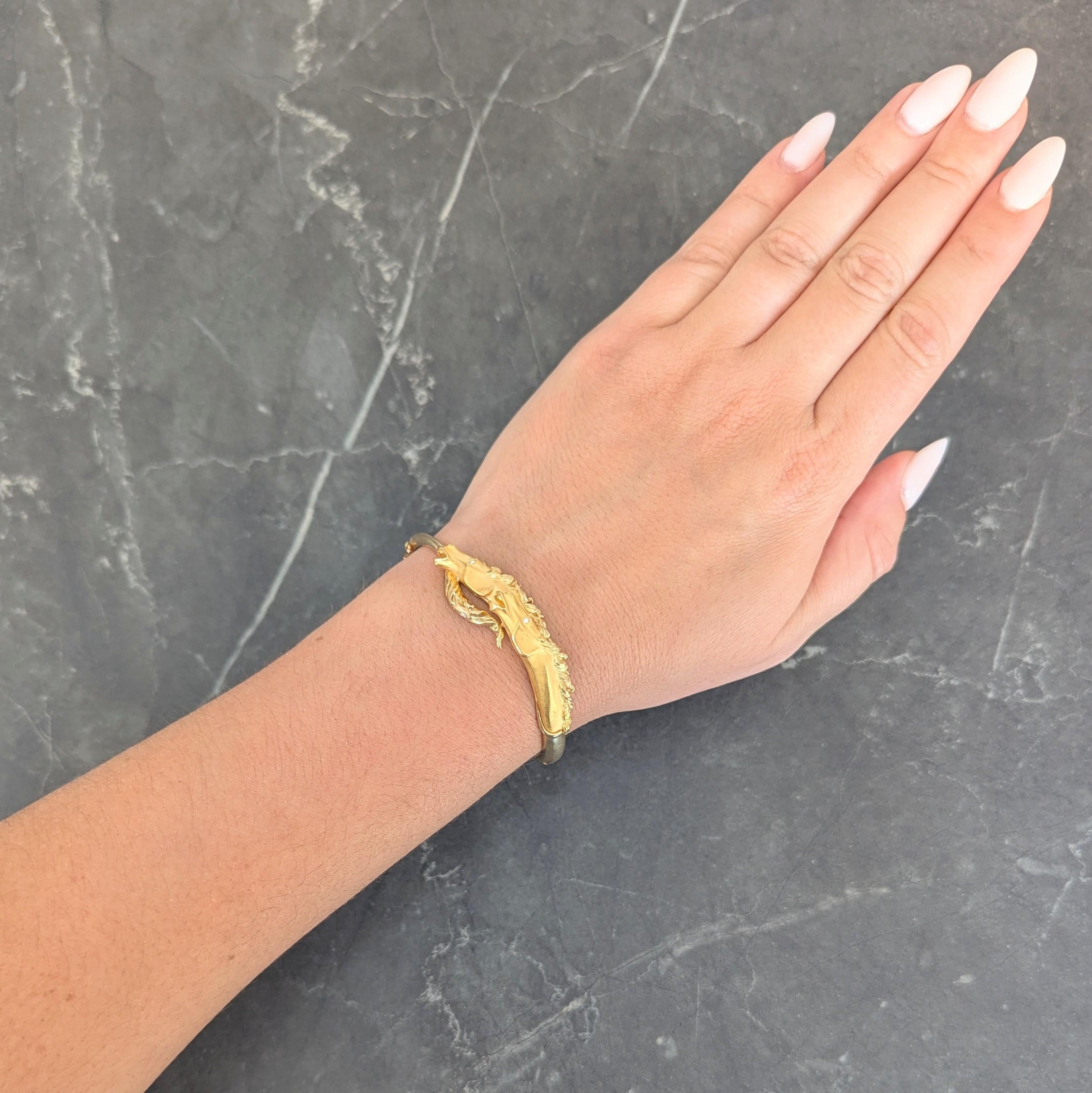 Designed bypass style and terminating with tail and two highly rendered gold horse heads
With groove matte faces and whipping high polished manes
Accented by flush set round brilliant cut diamond eyes
Weighing approximately 0.02 carat - eye
