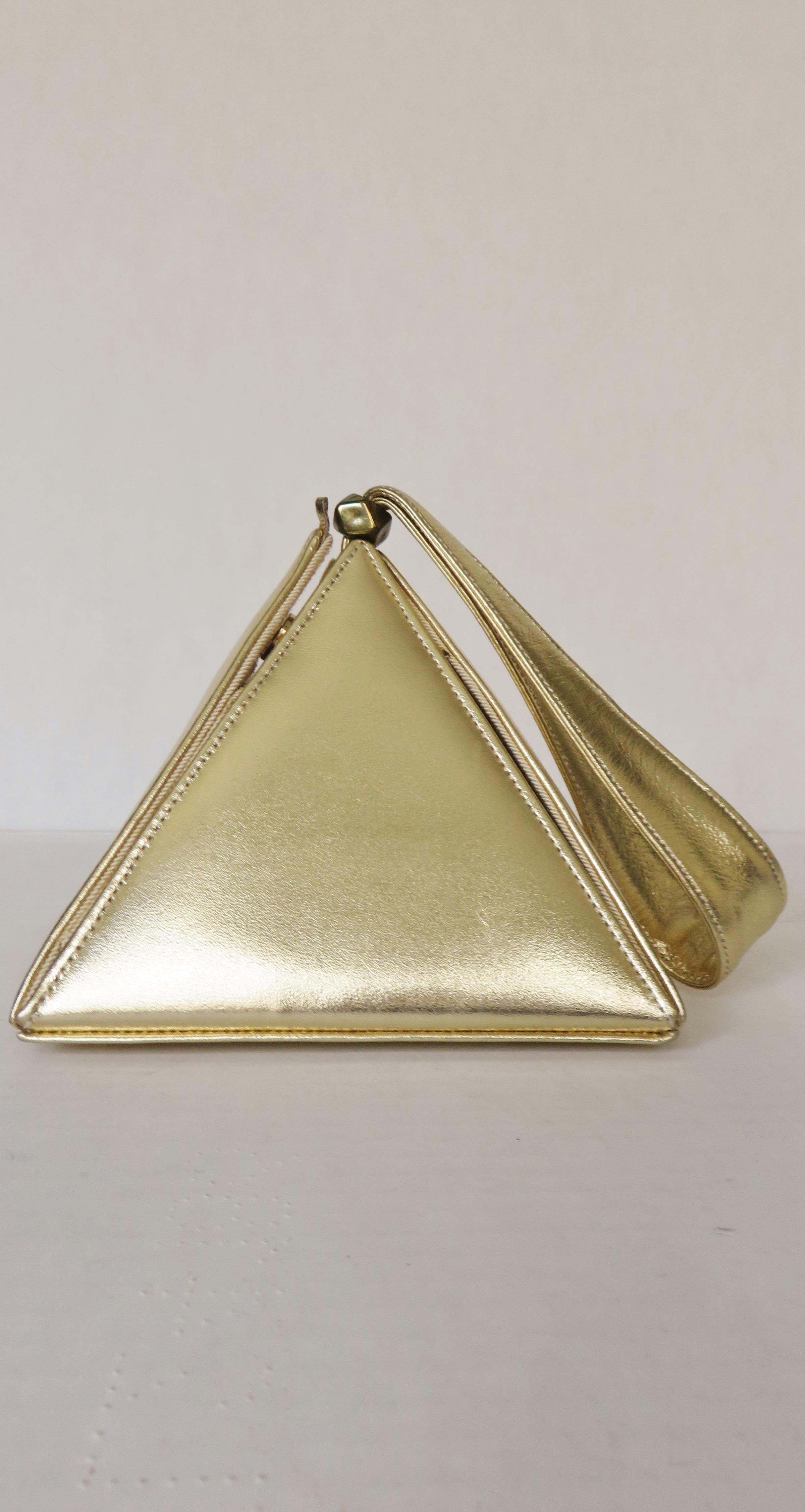 A gorgeous gold leather triangular box purse from Carey Adina.  It has 4 triangular panels emanating from a square base with small feet. One of these panels opens with a small tab and snaps closed.  It has a top handle and is lined in matching silk