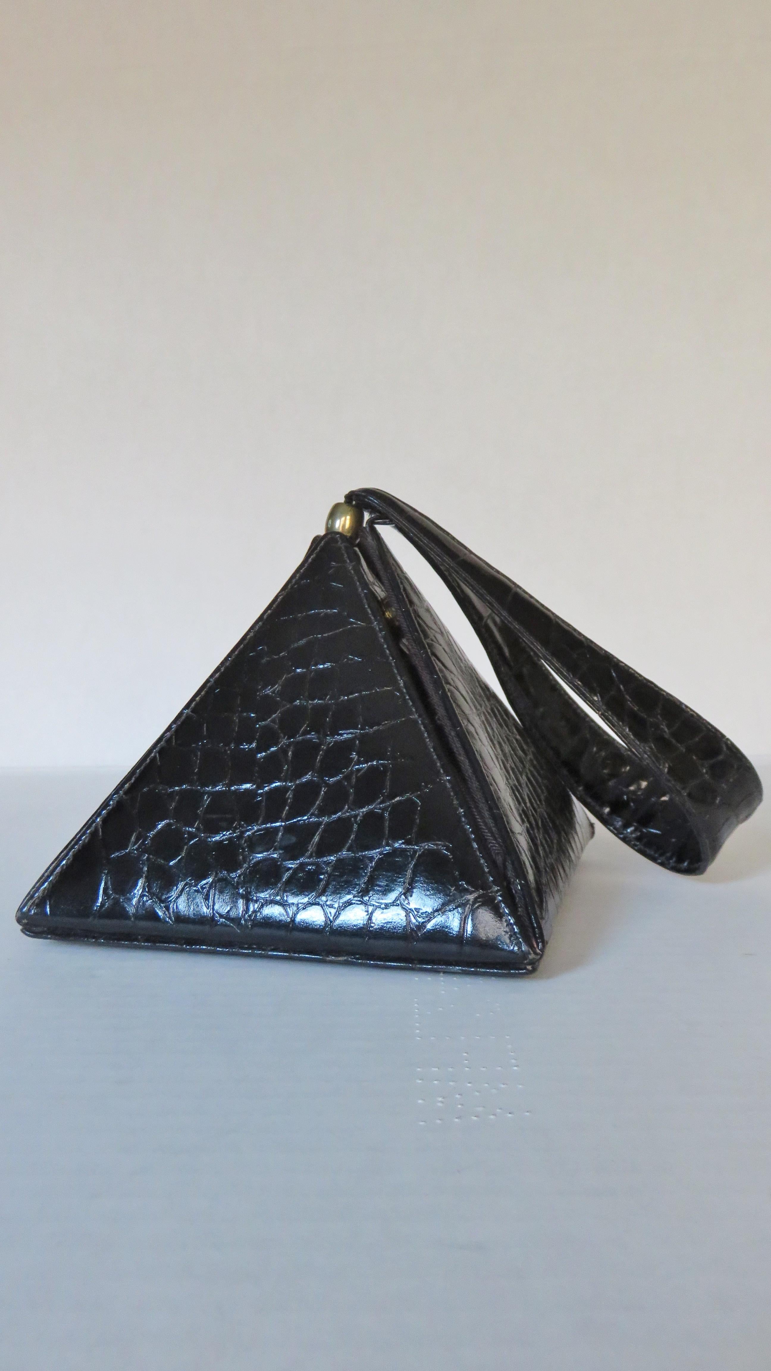 A gorgeous alligator embossed black leather triangular box handbag from Carey Adina.  It has 4 triangular panels emanating from a square base with small gold feet. One of these panels opens with a small tab and magnetically snaps closed.  It has a