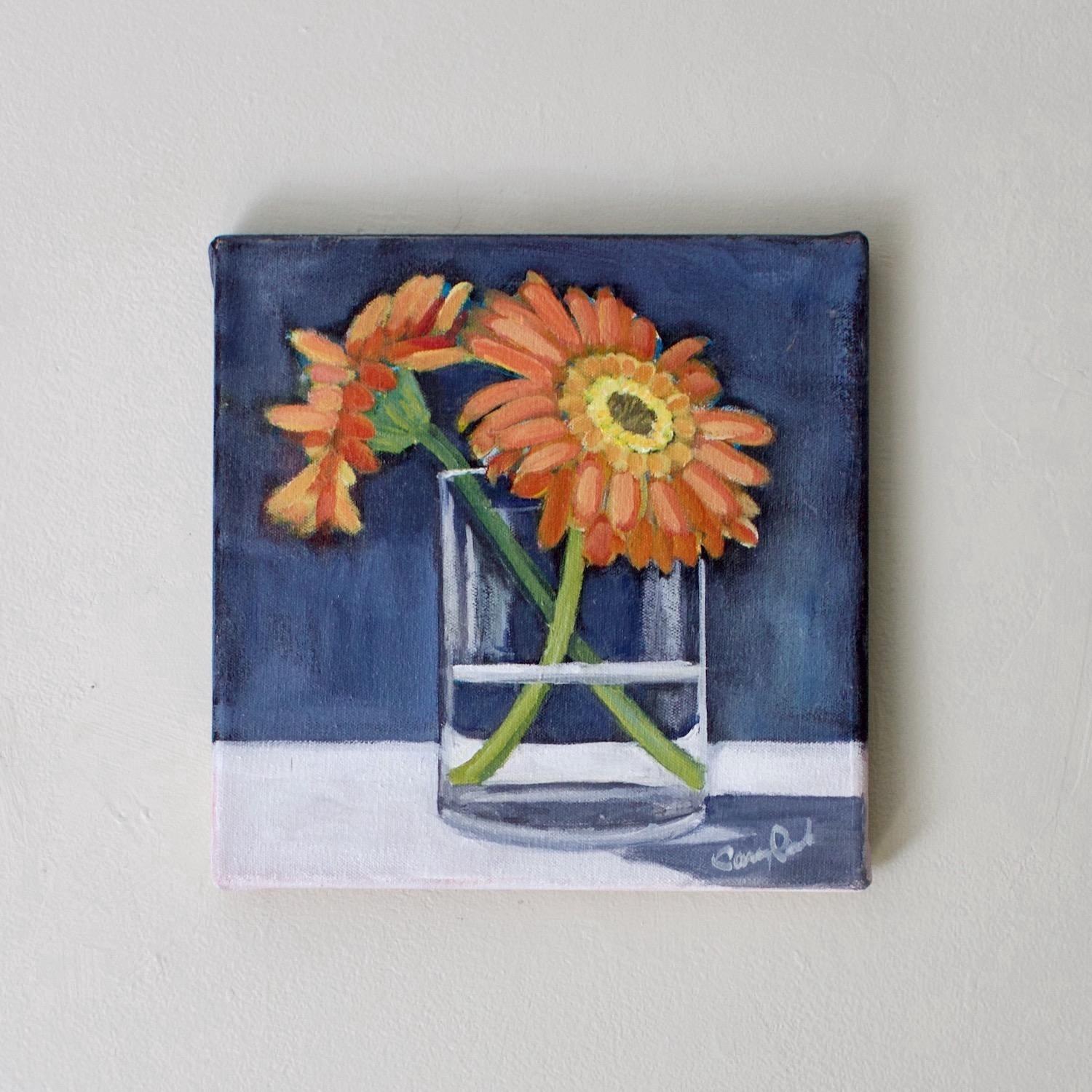 <p>Artist Comments<br />Two bright orange flowers contrast against a deep blue background. Their sturdy green stems cross elegantly within a clear glass, while the petals fan out in a delicate display. The simple details and vibrant colors add charm