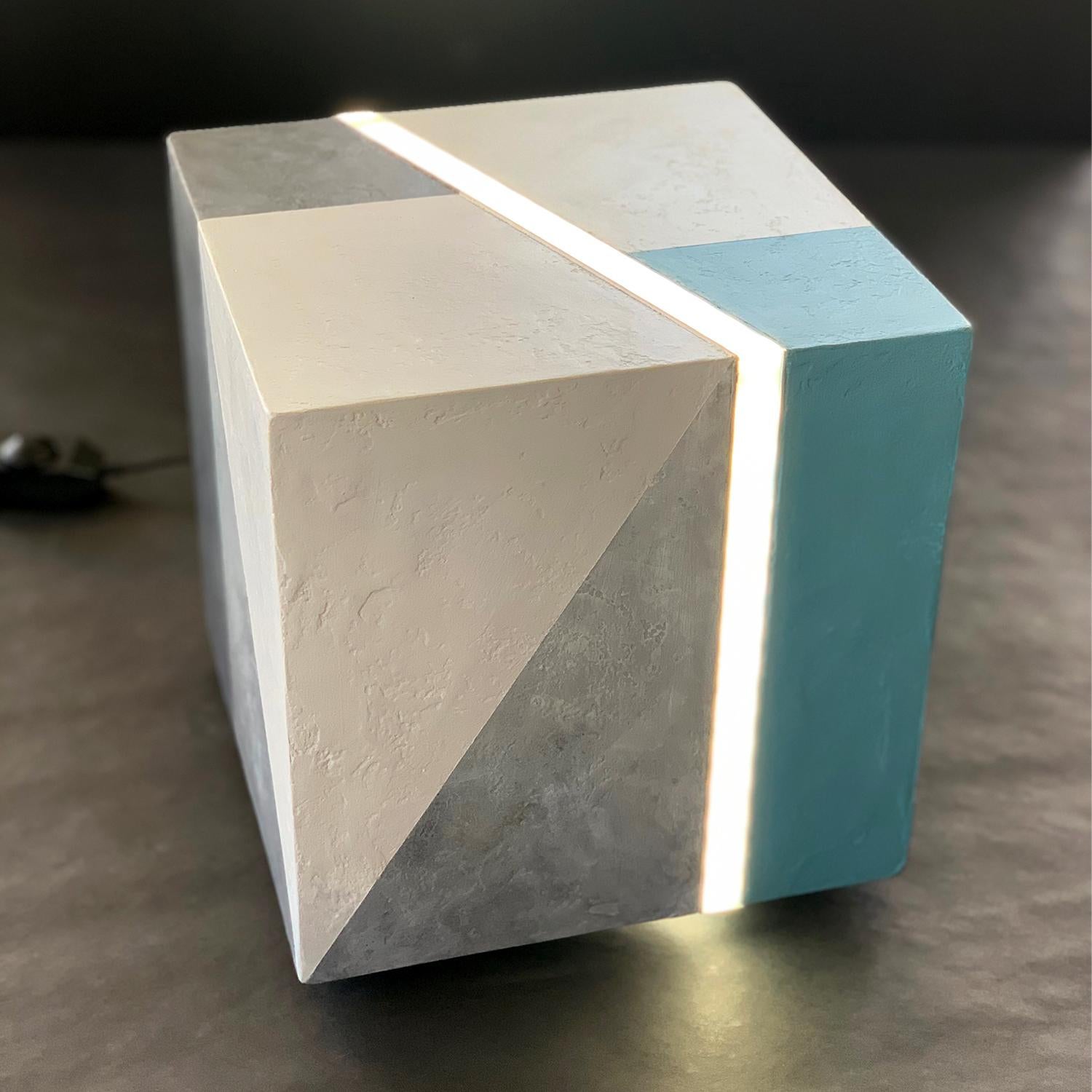 This sculpture light is a captivating addition to the Art + Light series, where the interplay of light and art creates a unique and fascinating effect. The wooden cube is covered with mixed media and painted with acrylic, giving it an exceptional