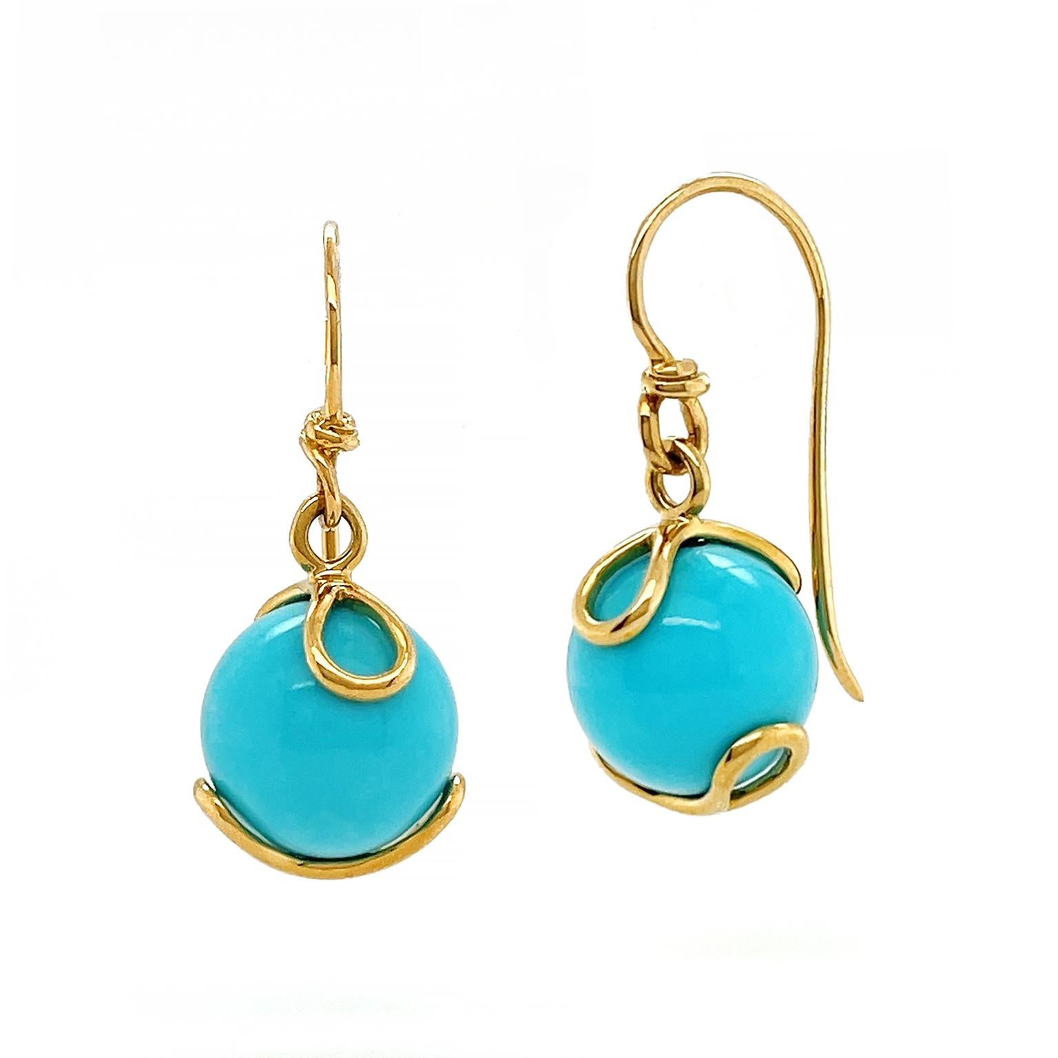 The warm shade of gold complements the cool tone of turquoise. 18k yellow gold french hooks with knotted detailing secure gold loops sheltering an orb of turquoise. The gem is polished, which further emphasizes its vivid cyan hue. The total weight