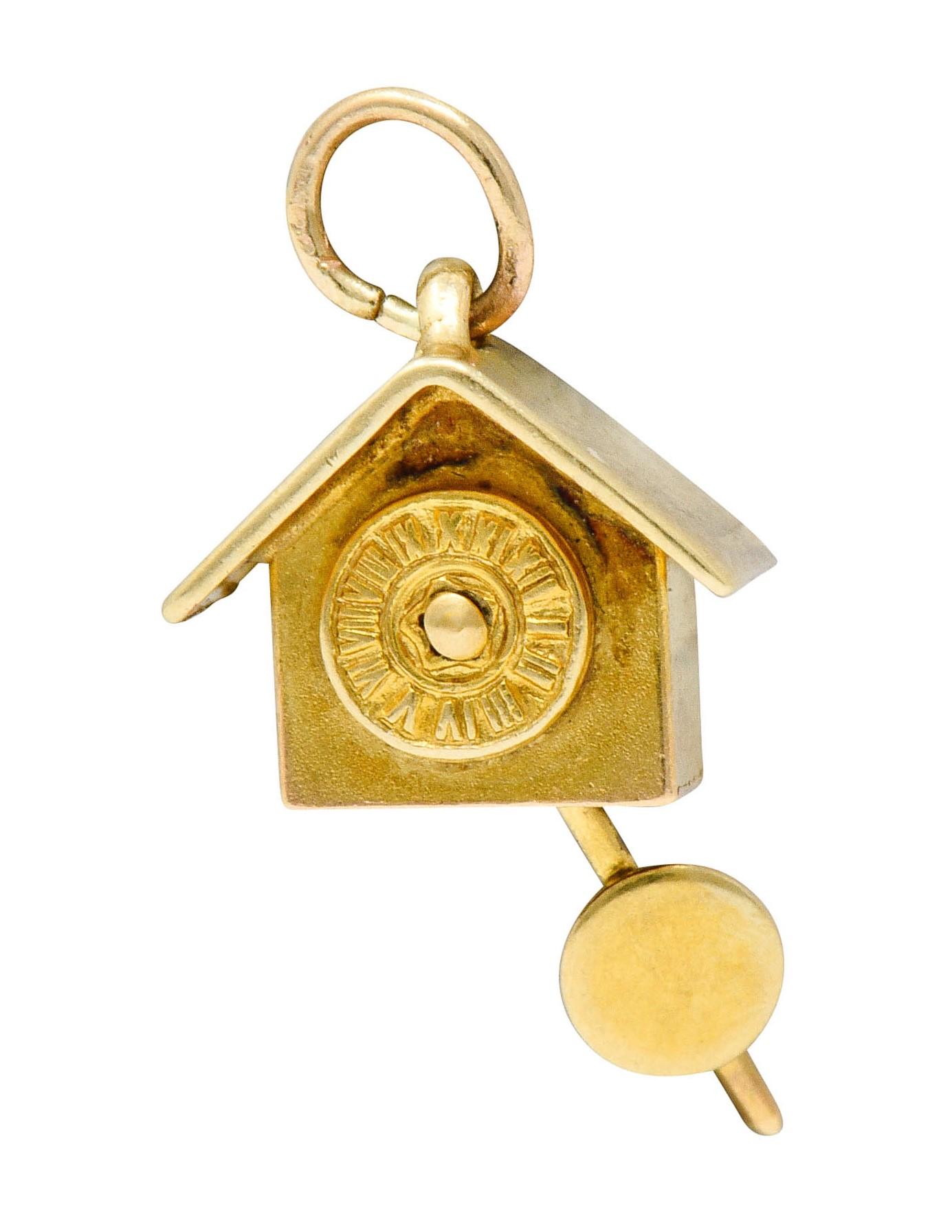 Designed as a cuckoo style clock with a pitched roof and circular face

Suspending an articulated pendulum

Completed by jump ring bale

Stamped 14KT for 14 karat gold

With maker's mark for Carl-Art Inc.

Circa: 1940s

Measures: 3/8 x 3/4