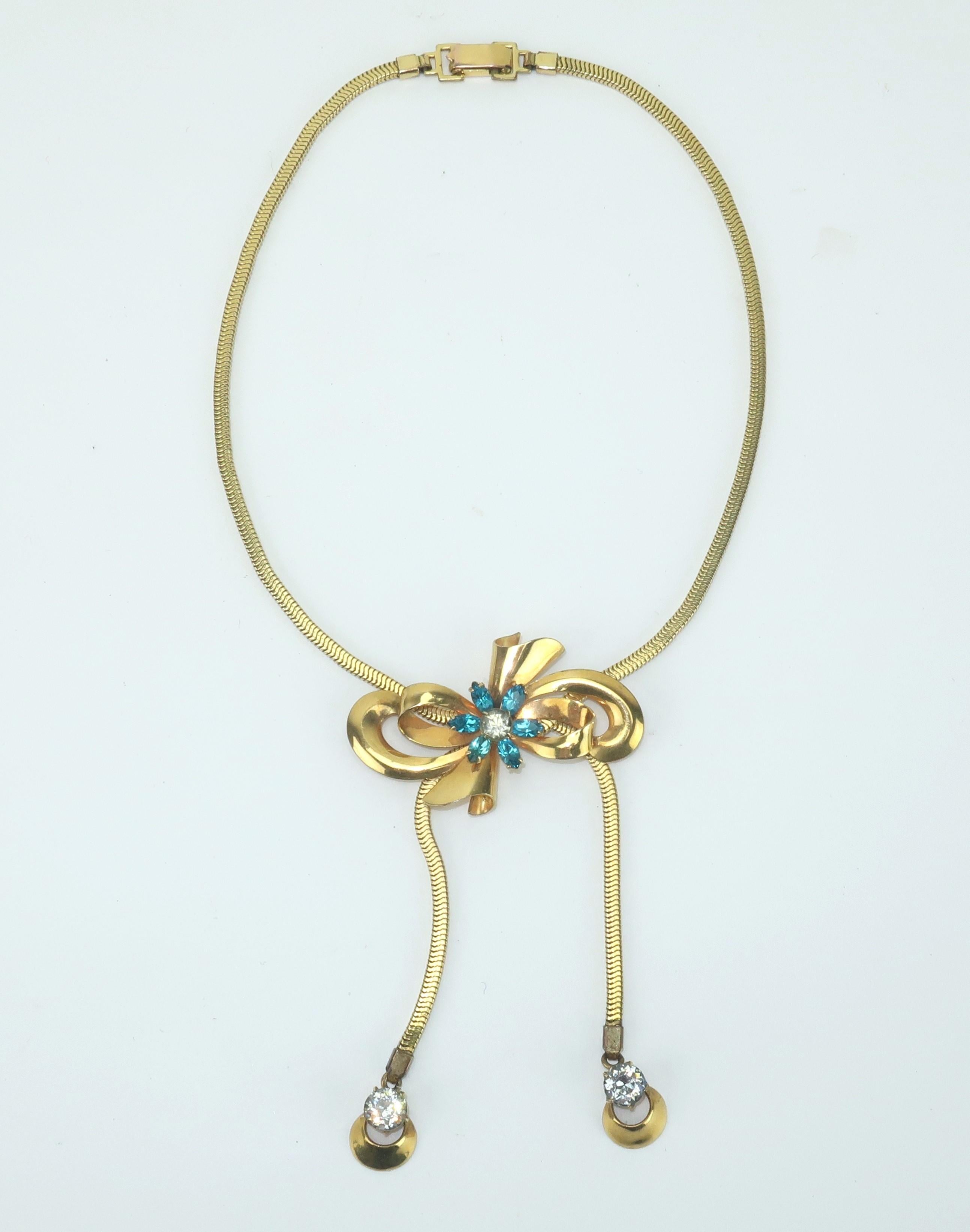Charming 1940's lariat style slide necklace by the American jewelry company, Carl-Art.  The necklace has a girlish aesthetic with a 12K gold filled bow design accented by rhinestones in crystal and aqua blue.  The unique slide mechanism at the back