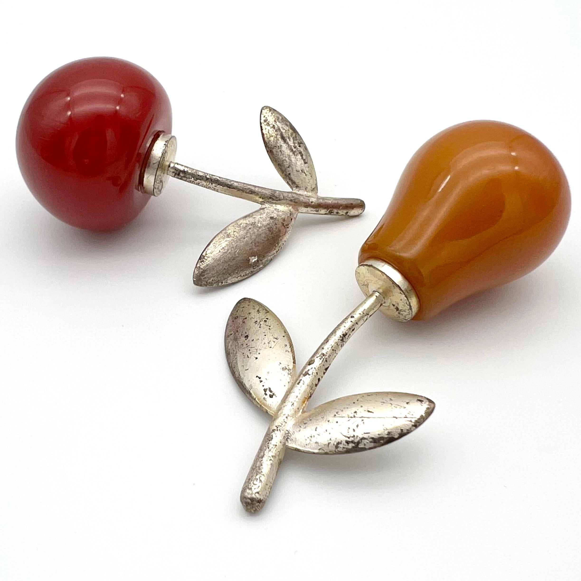 Art-Deco Salt and pepper shaker set. Prewar production - very early 30s.
The body of the shakers (apple and pear) is made of coloured Bakelite, the stems are of silver plated brass.
To open them, you can screw the stems off and on. 

Apple: