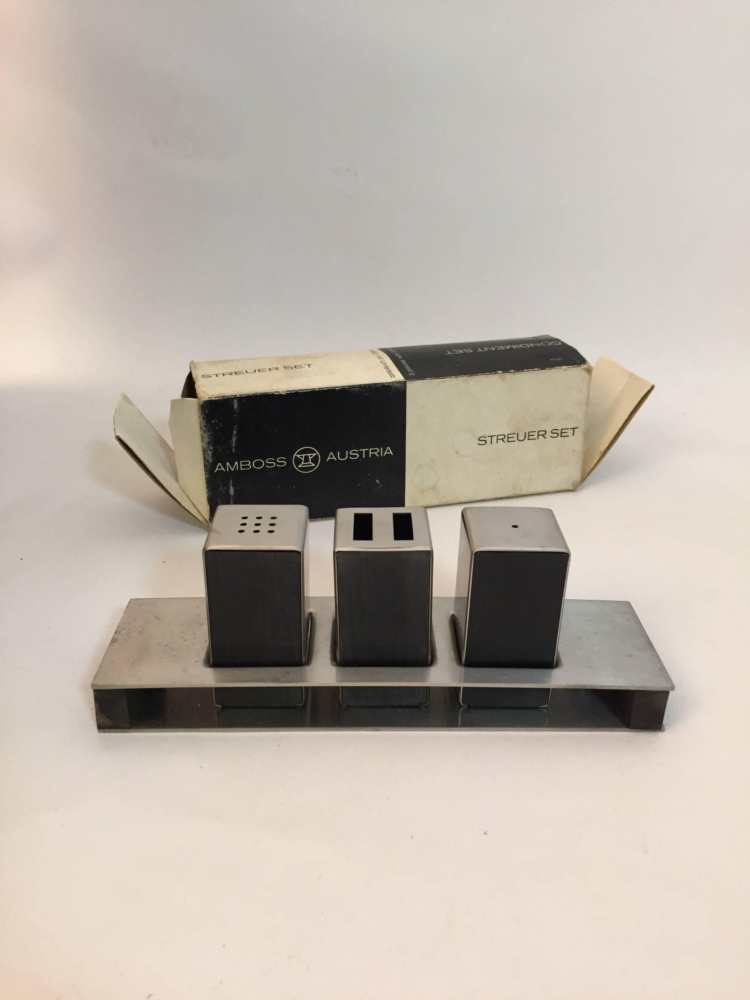 Minimalist design at its best by Carl Aubock. Stainless steel and plastic construction. The set consists of salt and pepper shakers, toothpick holder and tray. The item comes in the original box and has never been used, circa 1960. Fully signed,