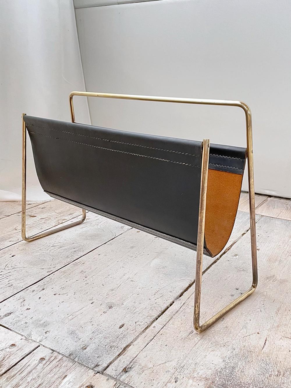 Huge timeless Austrian Mid-Century Modern newspaper/magazine stand no. 4488 designed by Carl Auböck II from early 1950s and manufactured by Auböck Werkstätte in Vienna. 
This magazine rack is original from 50's with the hand stitched black leather