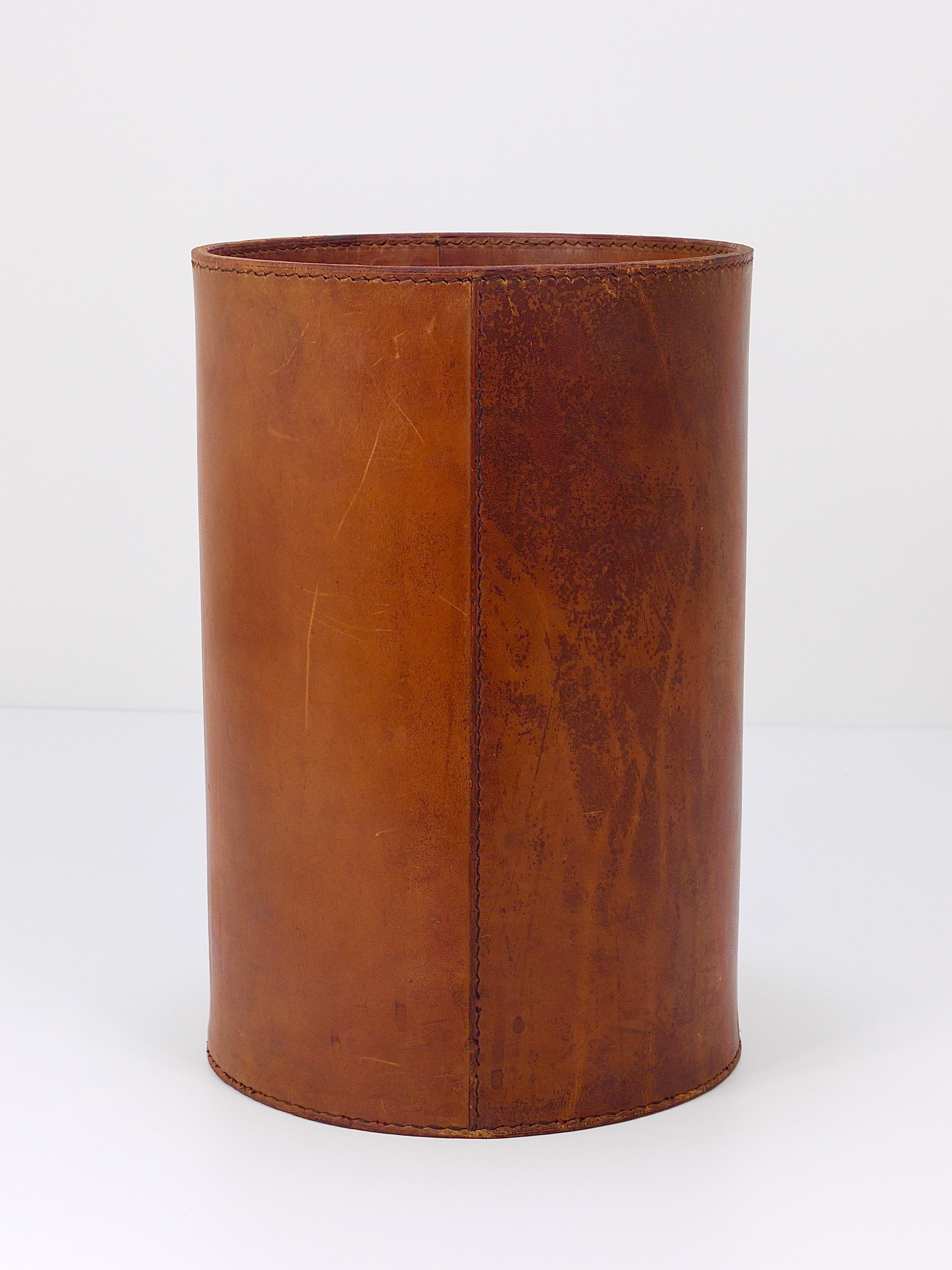 A beautiful and elegant, vintage Mid-Century Modern cylindric paper basket / paper bin from the 1950s. Designed an manufactured by Werkstätte Carl Aubock, Vienna / Austria. Handmade and hand-sewn from thick cognac brown tan saddle leather. In good