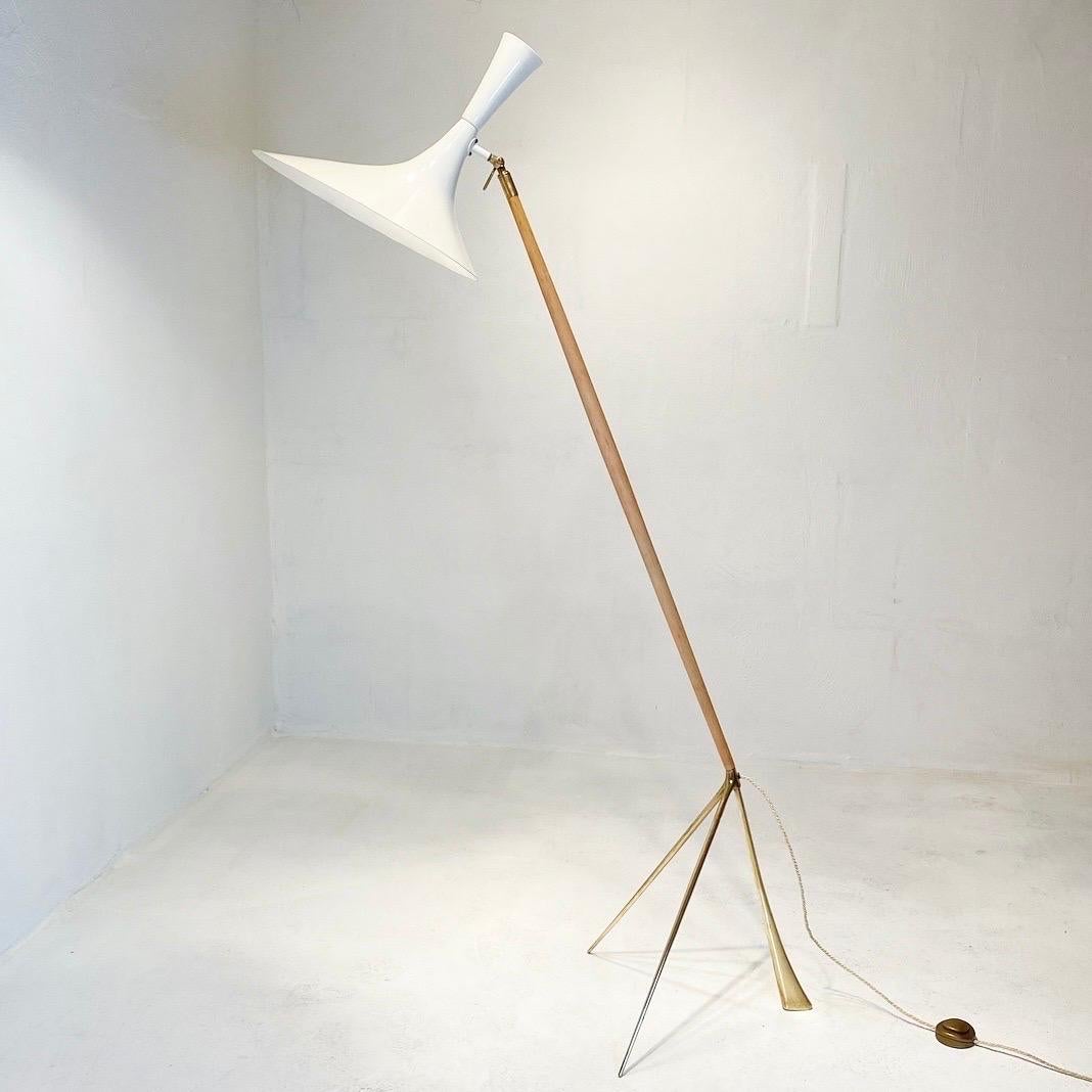 Floor lamp made of brass, probably ash or birch wood and a glossy white lacquered diabolo shade with two light sources.

The base made of solid brass makes the light sturdy. The light head which consists of both up and down light can be directed in