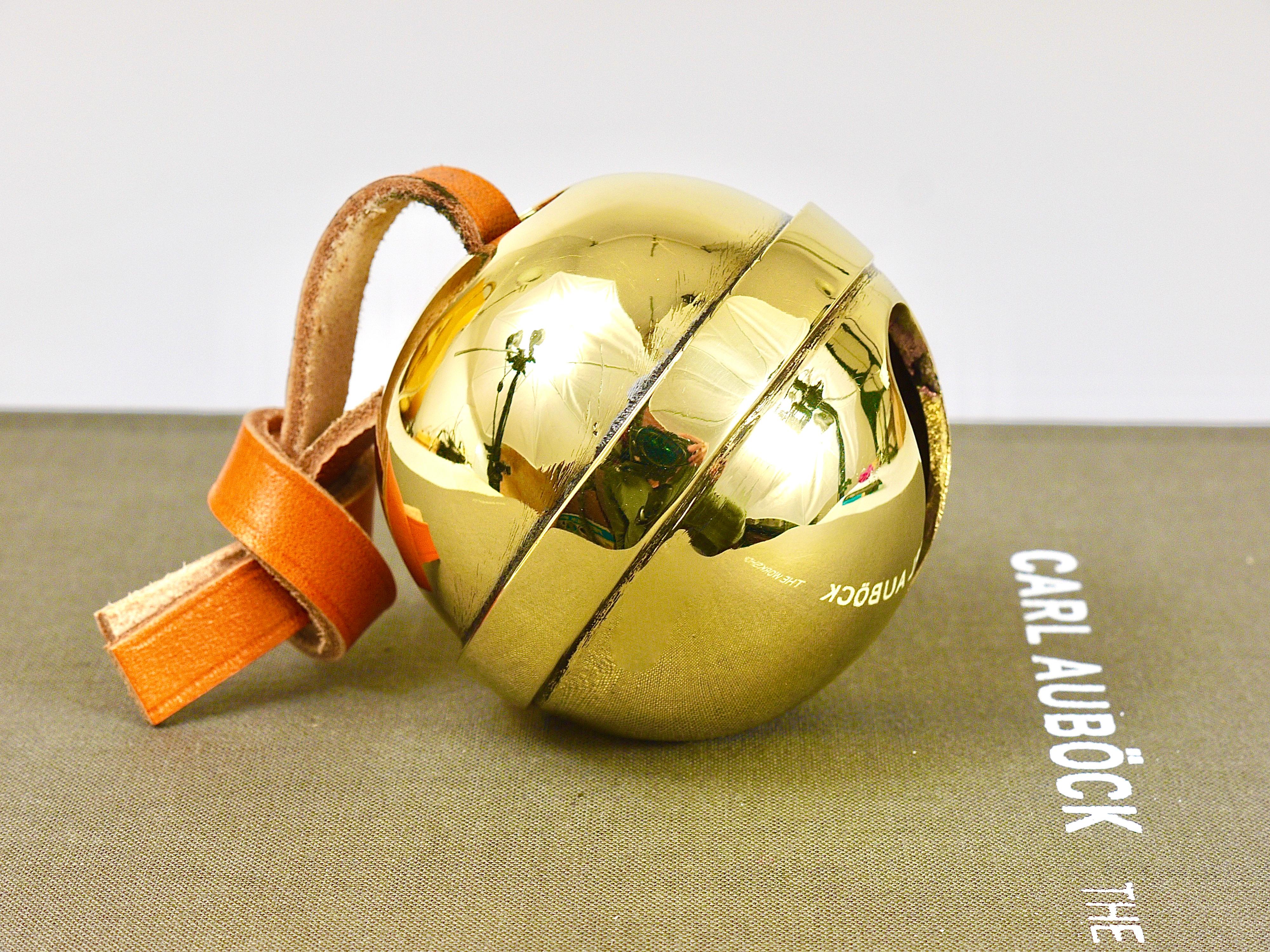 A handmade paperweight in the shape of a sleigh bell, model #5039, originally designed by Carl Aubock III back in the 1960s. A very charming piece, reissued by Werkstätte Auböck in Vienna / Austria. Handmade of polished brass with a leather strap,