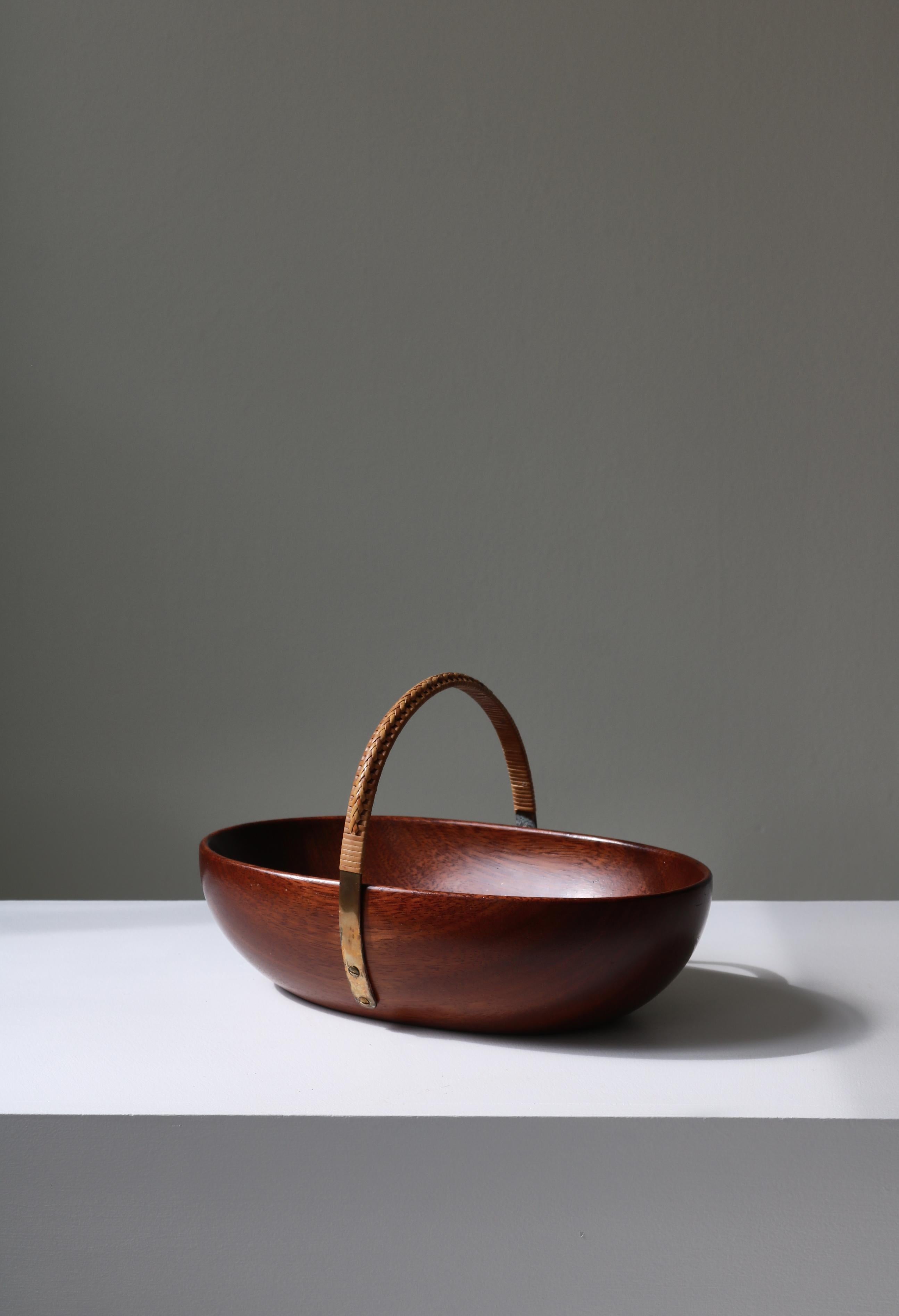 Wonderful nut bowl by Carl Auböck II handmade in his workshop in Vienna, Austria, 1955. Made out of carved mahogany, the bowl has a brass handle that follow the shape of the same bowl and is covered in wicker. Great condition with no breaks or