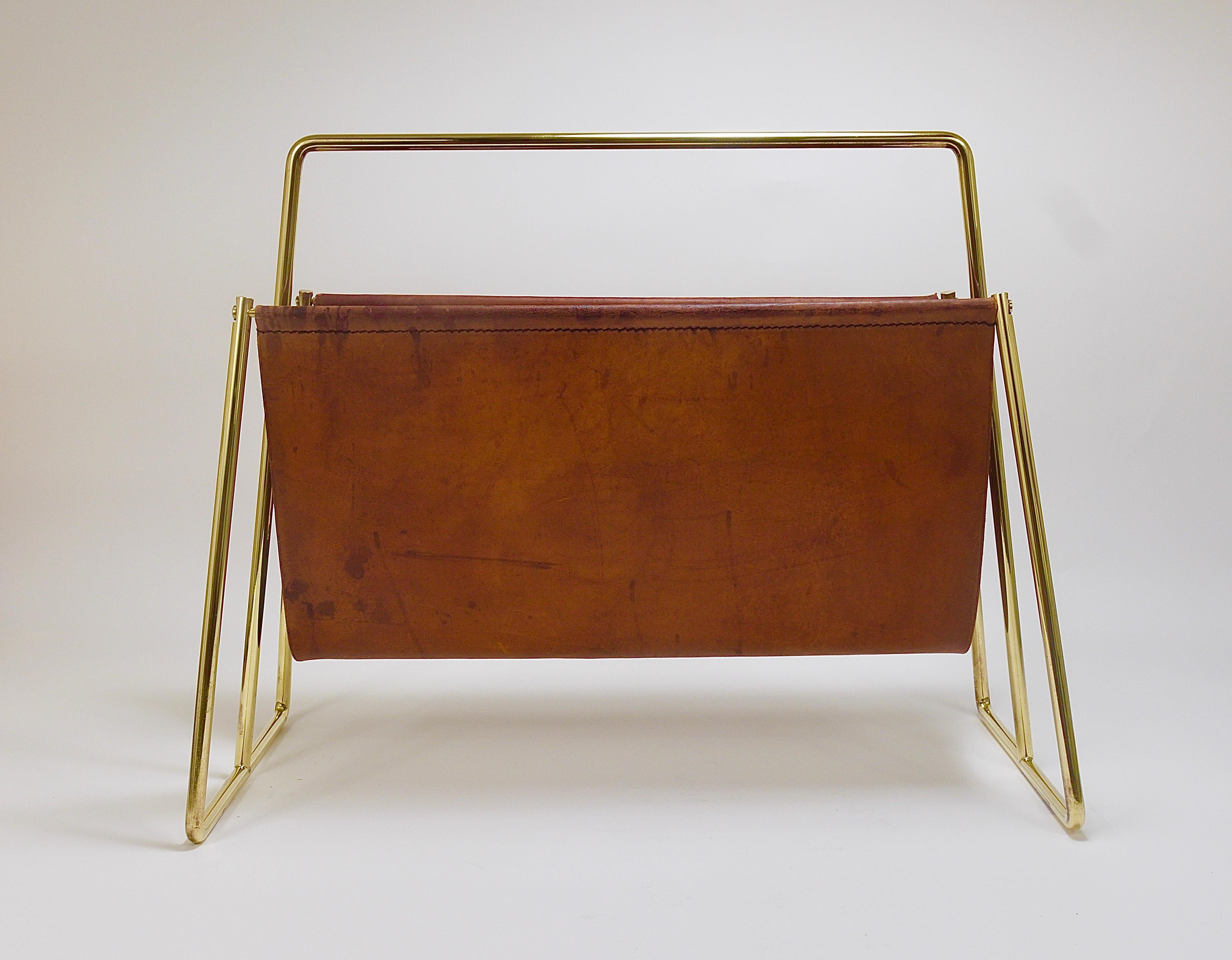 A beautiful midcentury original and old newspaper stand / magazine rack from the 1950s. This is the large double-sided model No. 4101. Designed and manufactured by Carl Auböck in Vienna, Austria. Its solid brass frame has been polished by hand and