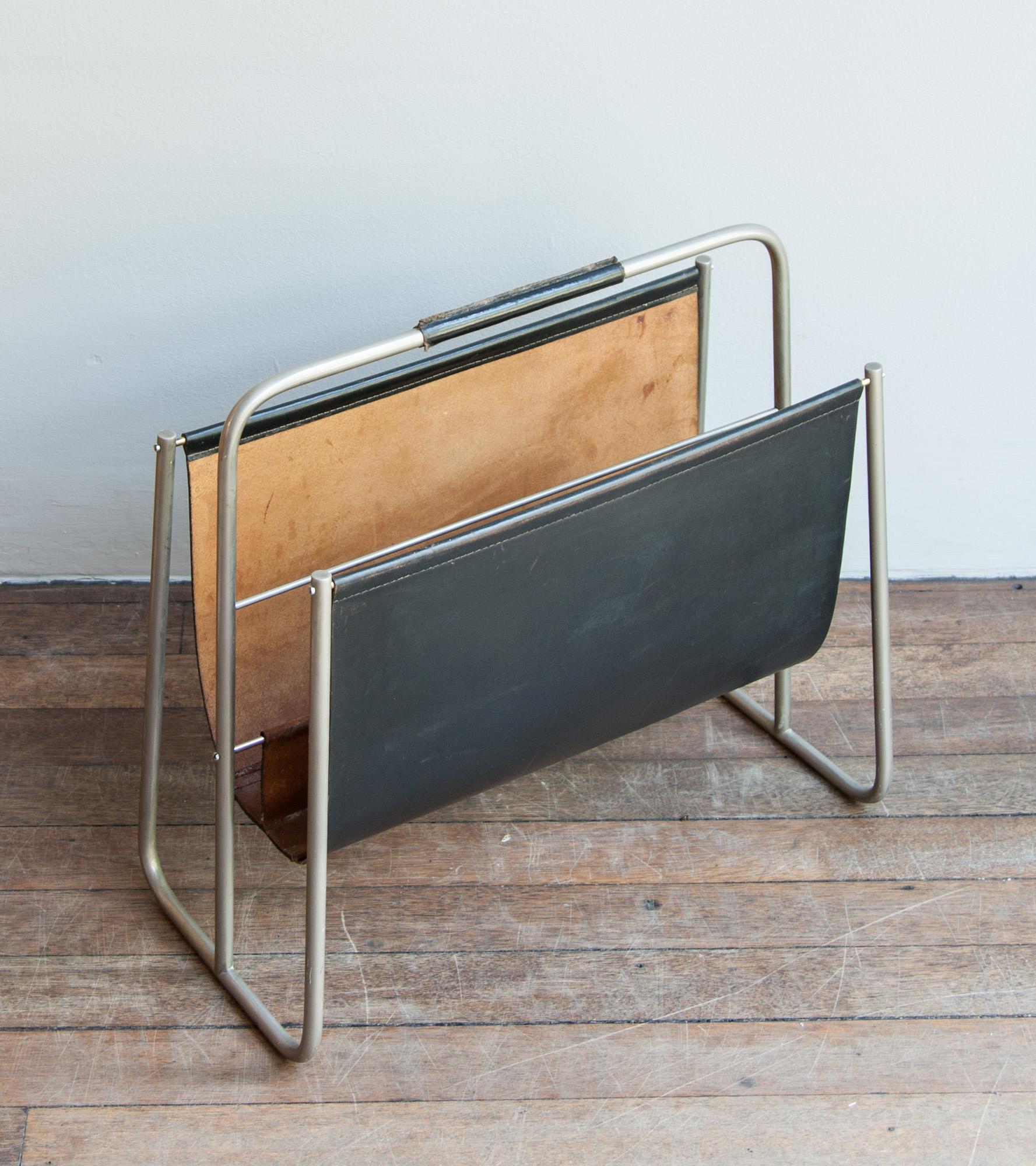 Vintage magazine rack by Carl Auböck II, Vienna, circa 1950.
The sling and the handle are made of black-colored leather and have stitching of the same color; the frame is made of matte nickel-plated brass and is covered by a uniform natural