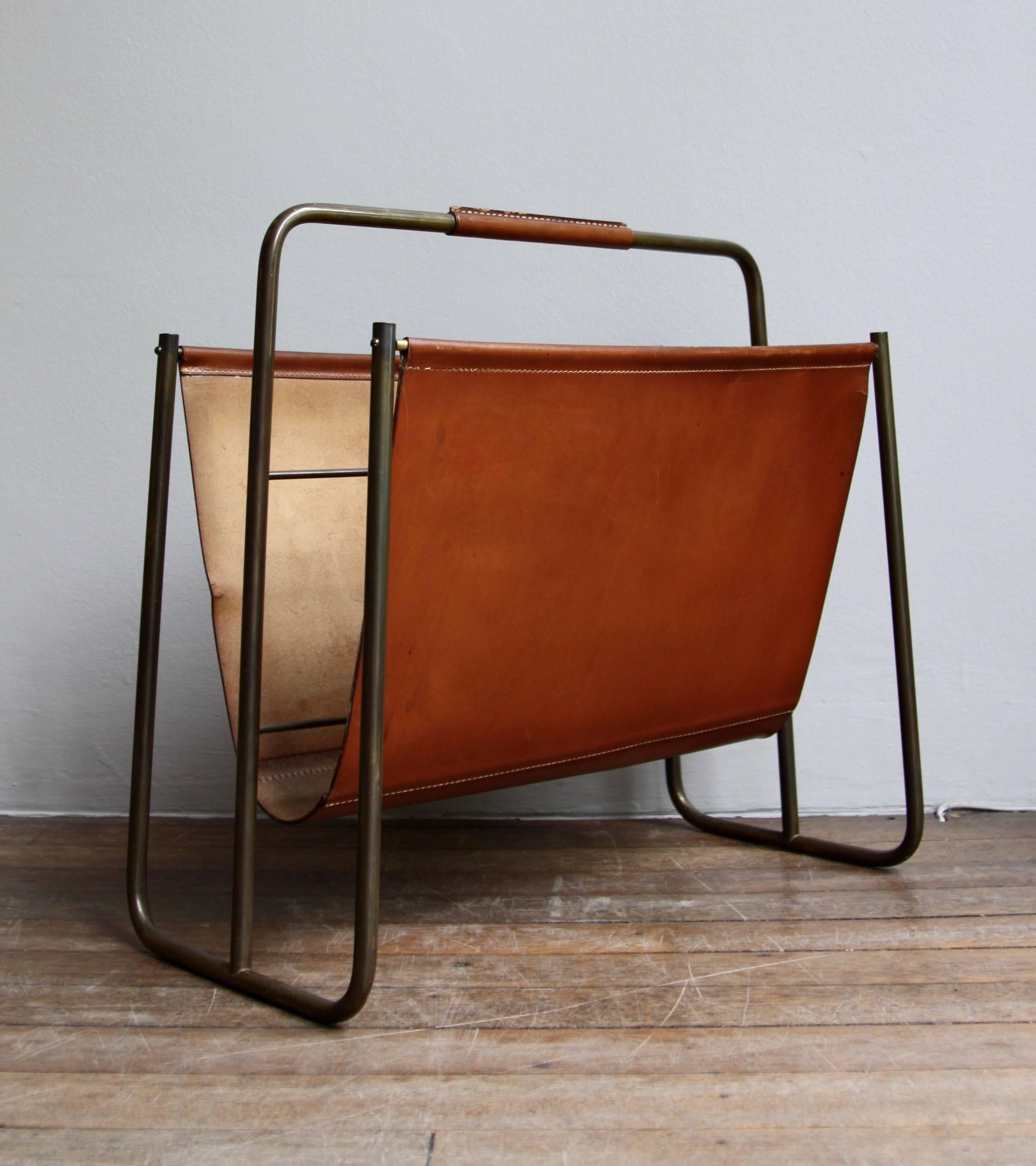 A vintage magazine holder designed and made by Carl Auböck II, Vienna, circa 1950. The rich-clay-coloured leather sling and cladding on the handle is completely original and boasts a luscious patina. Similarly, the geometric brass frame is covered