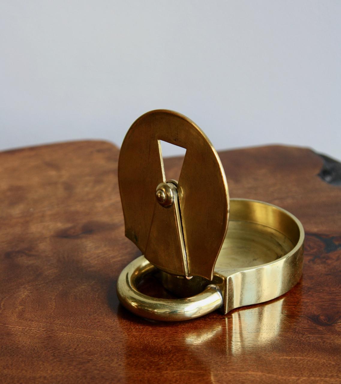 A rare model 3317 cast brass ashtray/trinket box in the form of a padlock designed by Carl Auböck II in 1935 and made by Werkstätte Carl Auböck between 1935 and 1940.
The escutcheon swings left and right to allow passage through to the space inside