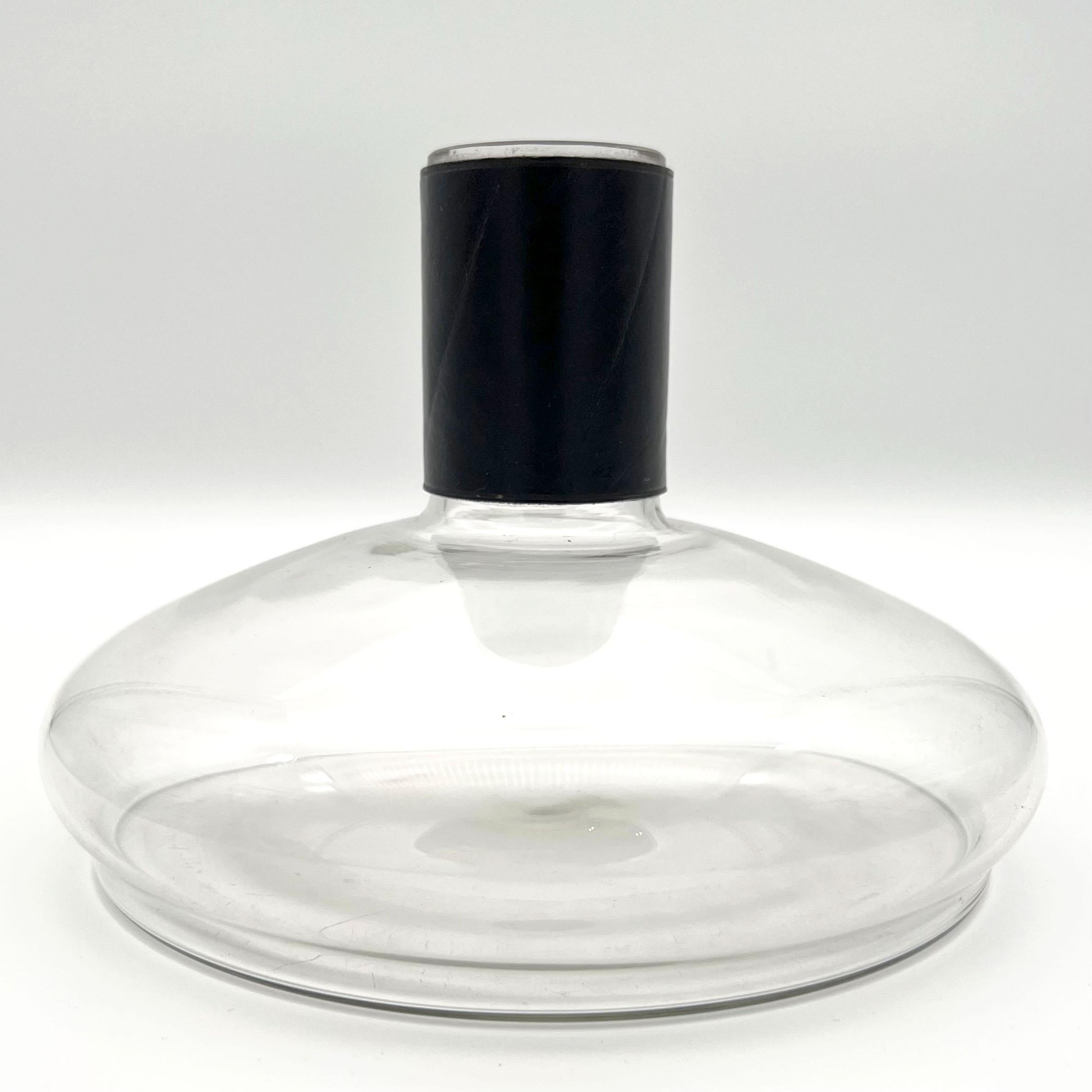Carl Auböck II vase or decanter, 1950s, Made in Austria.
A glass decanter/ vase with a hand sewn leather drip stop/ leather-bound sleeve on the neck of the bottle.
Pictured in the catalog 