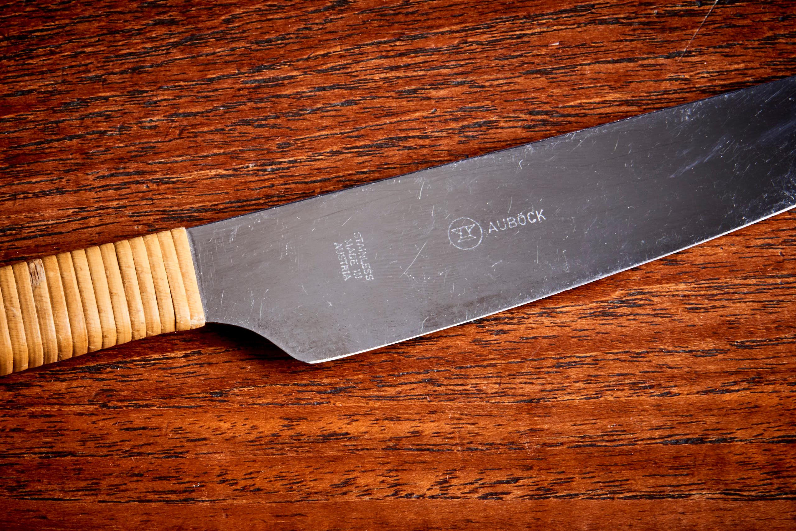 This knife made by Carl Auböck has a straight metal blade with a handle wrapped in rattan for grip. Its design is simple and functional, without any decorative elements, focusing on practicality and ease of use. The total length is 26,5cm, the blade