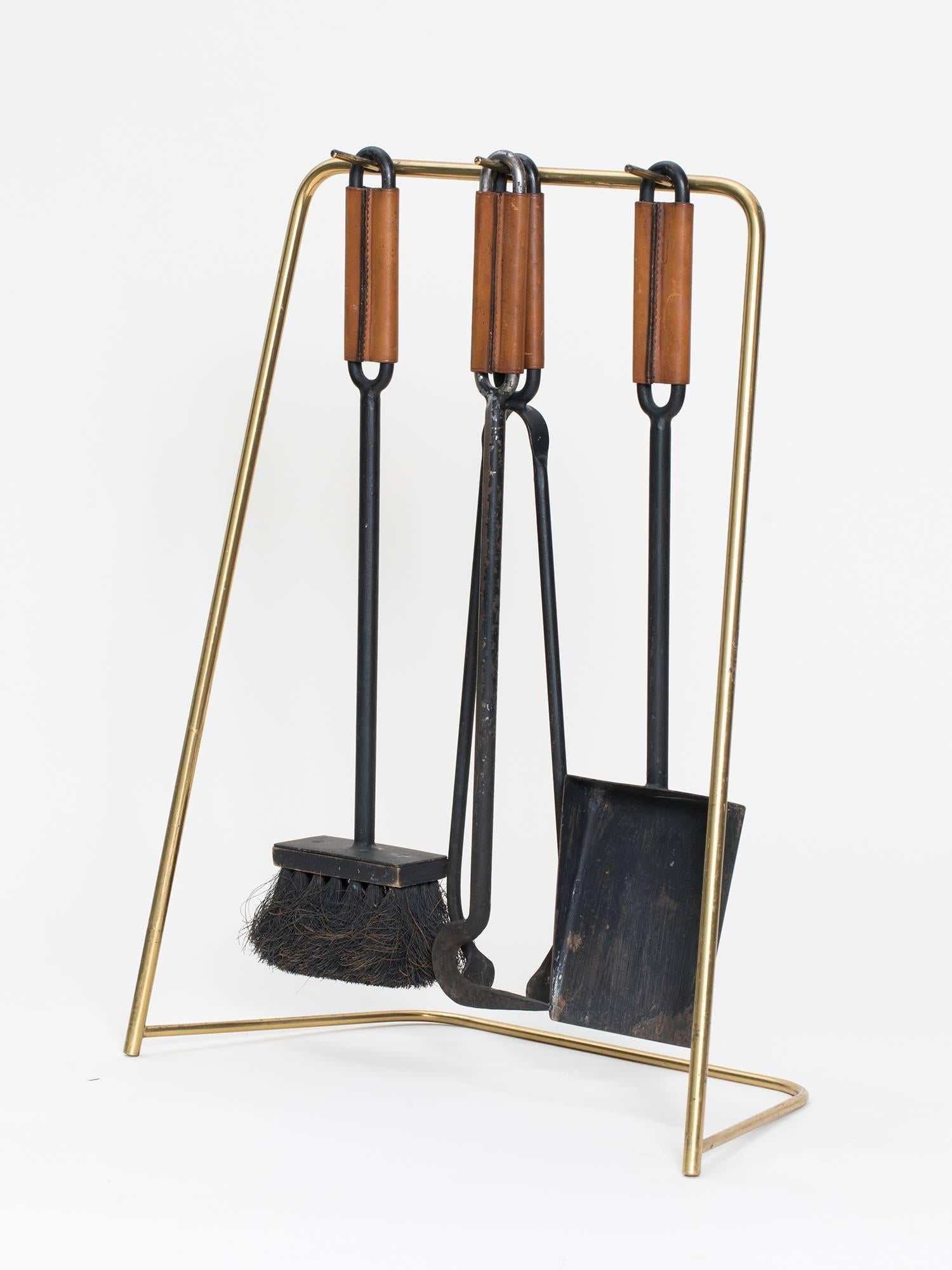 Iron and leather fire tool set with brush, hook, log grabber, shovel and brass stand by Viennese designer Carl Auböck. This is an original work from the 1950s.