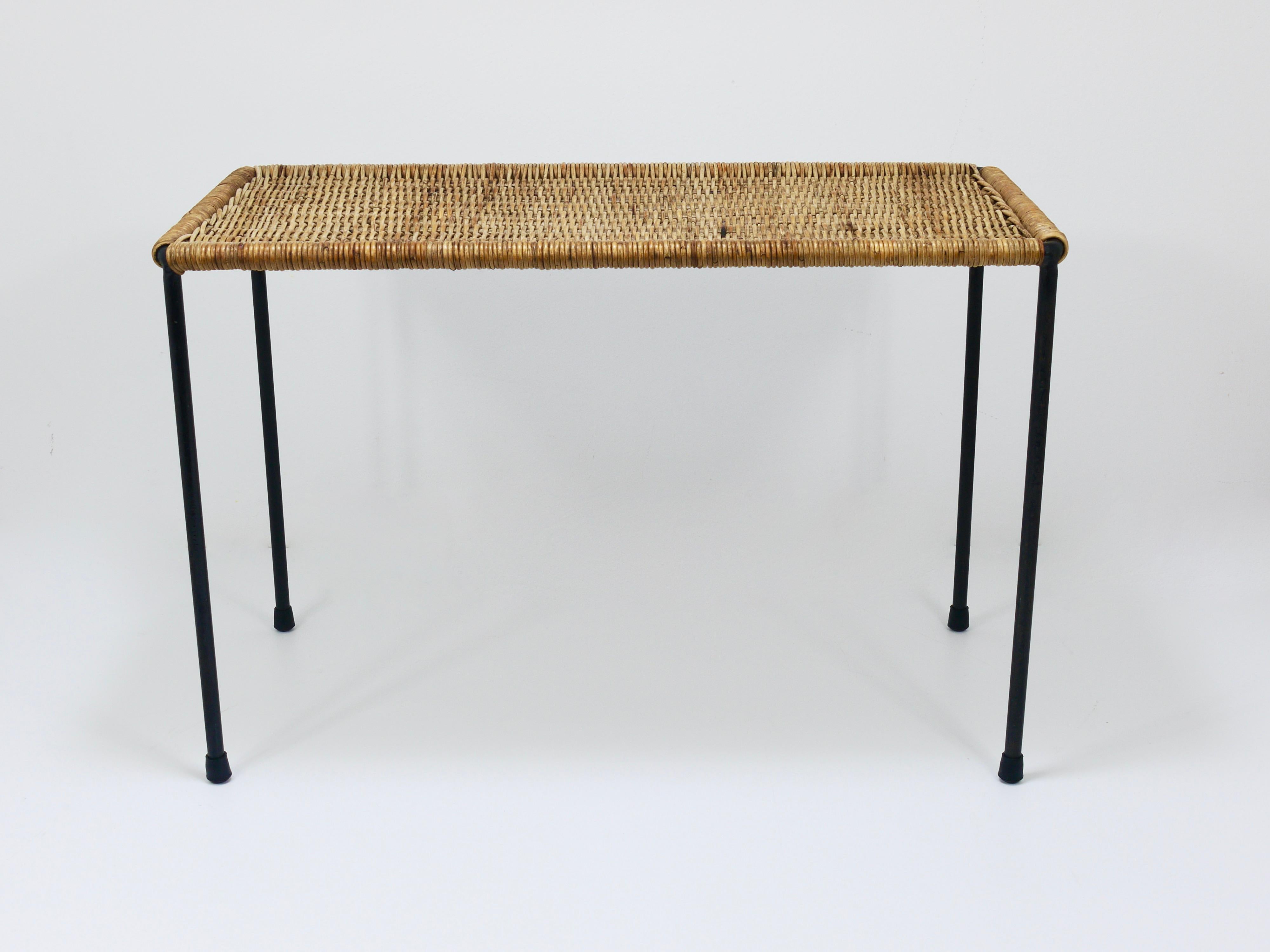 A beautiful rectangular Mid-Century side table / bench from the 1950s. This authentic vintage minimalistic piece was designed by Carl Auböck from Vienna and was crafted by Werkstätte Auböck, hand-woven from wicker. It features a black-finished iron
