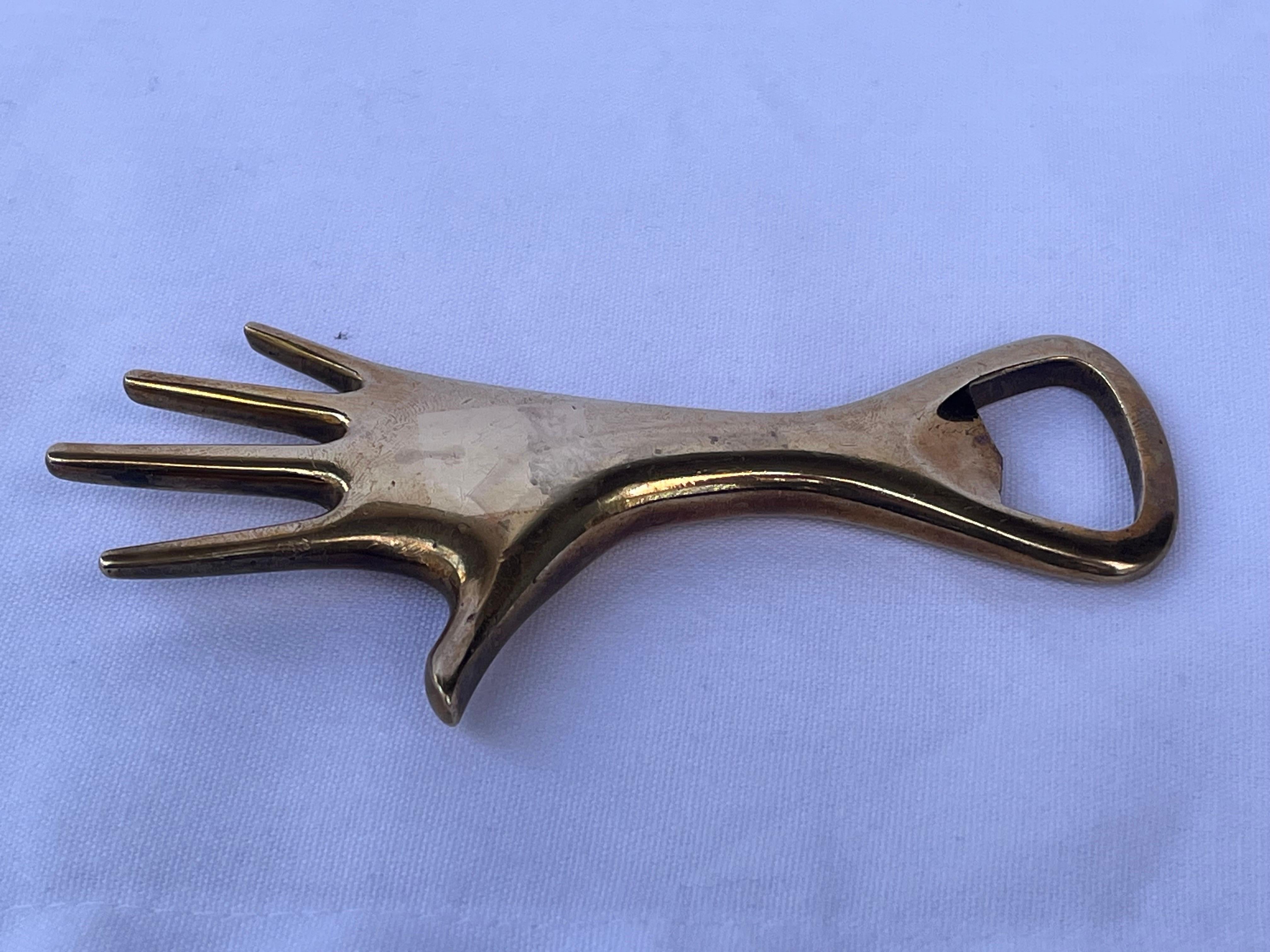 A vintage, mid century figural hand bottle opener designed by Carl Aubock and stamped Made In Austria. In vintage condition with a beautiful patina with the requisite nicks and marks indicating a life well lived and loved to this solid brass desk