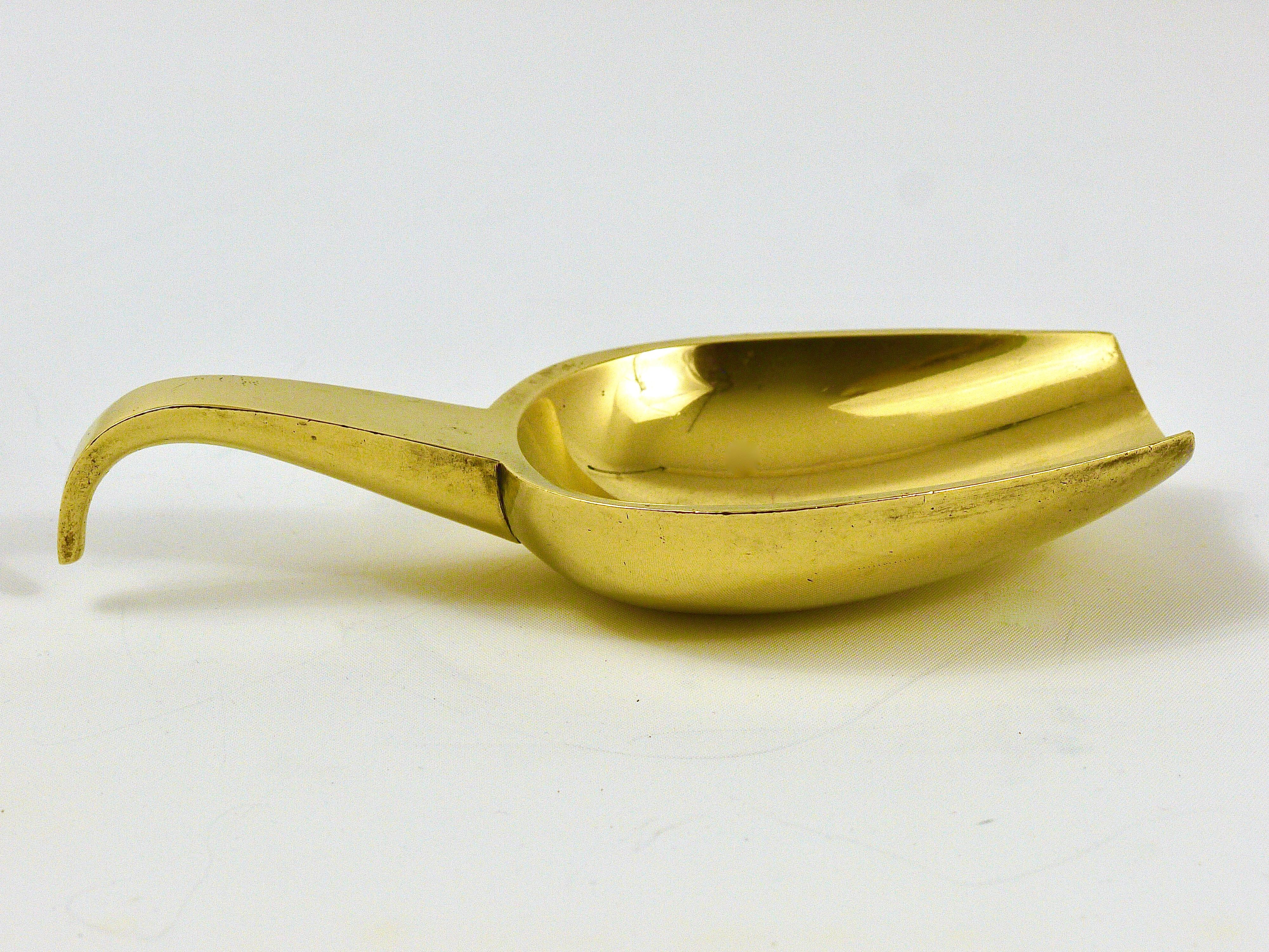 A very beautiful and solid polished brass modernist ashtray with handle in the shape of a shovel, designed and executed by Carl Auböck in the 1950s. Marked. In good condition with patina.