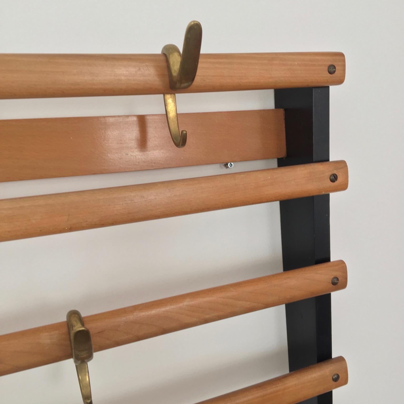 Wall-mounted coat rack by Carl Auböck, Vienna circa 1950 made of beechwood. The sides are lacquered black and slats colorless. Also comes with nine brass hooks. This original piece has a good vintage patina and condition.
Measures: 120 cm